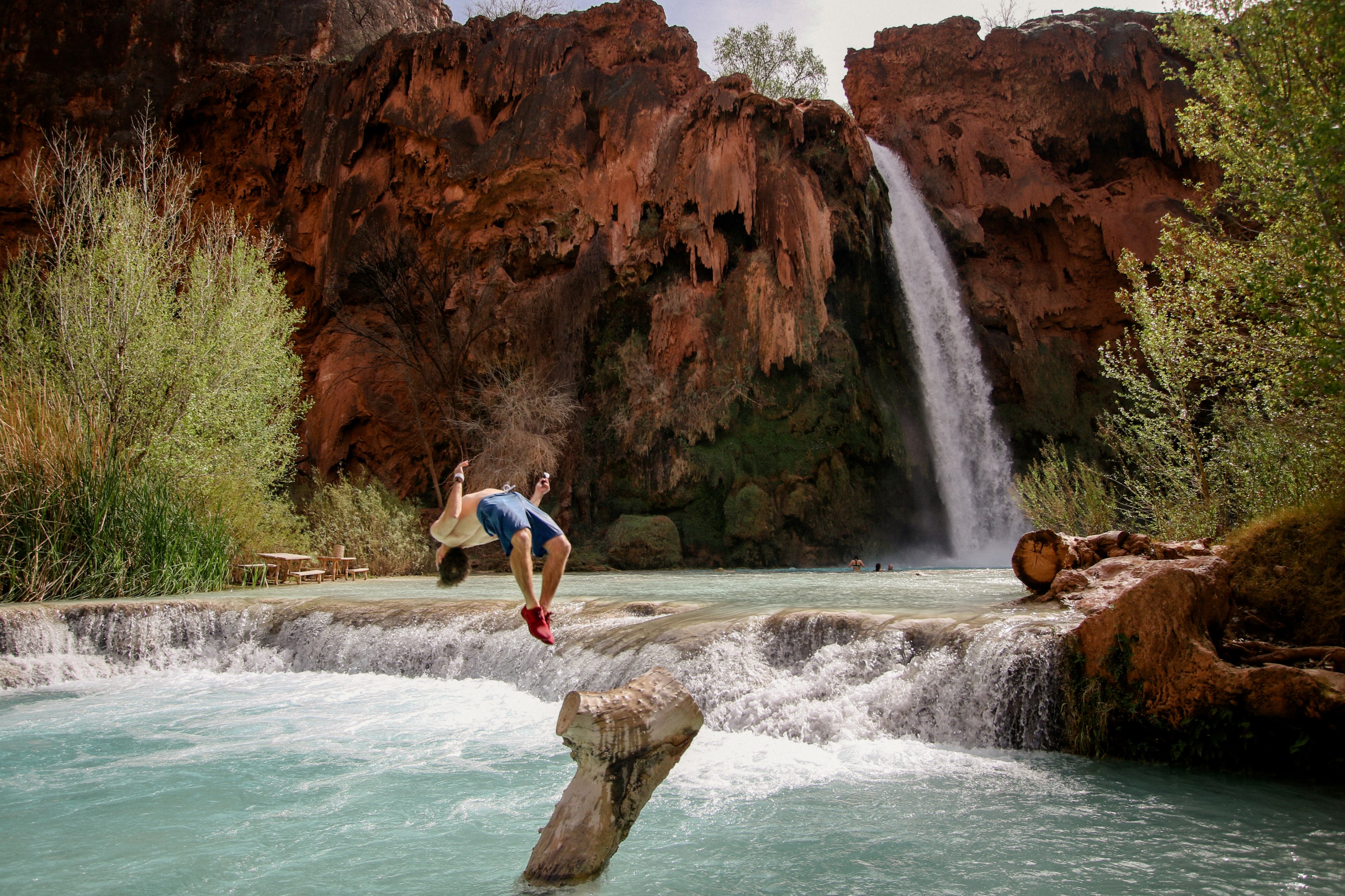 a person does a backflip into the water at a mountain pond at the bottom of a tall waterfall, waterfall into mountain pond 4k, HD Wallpaper