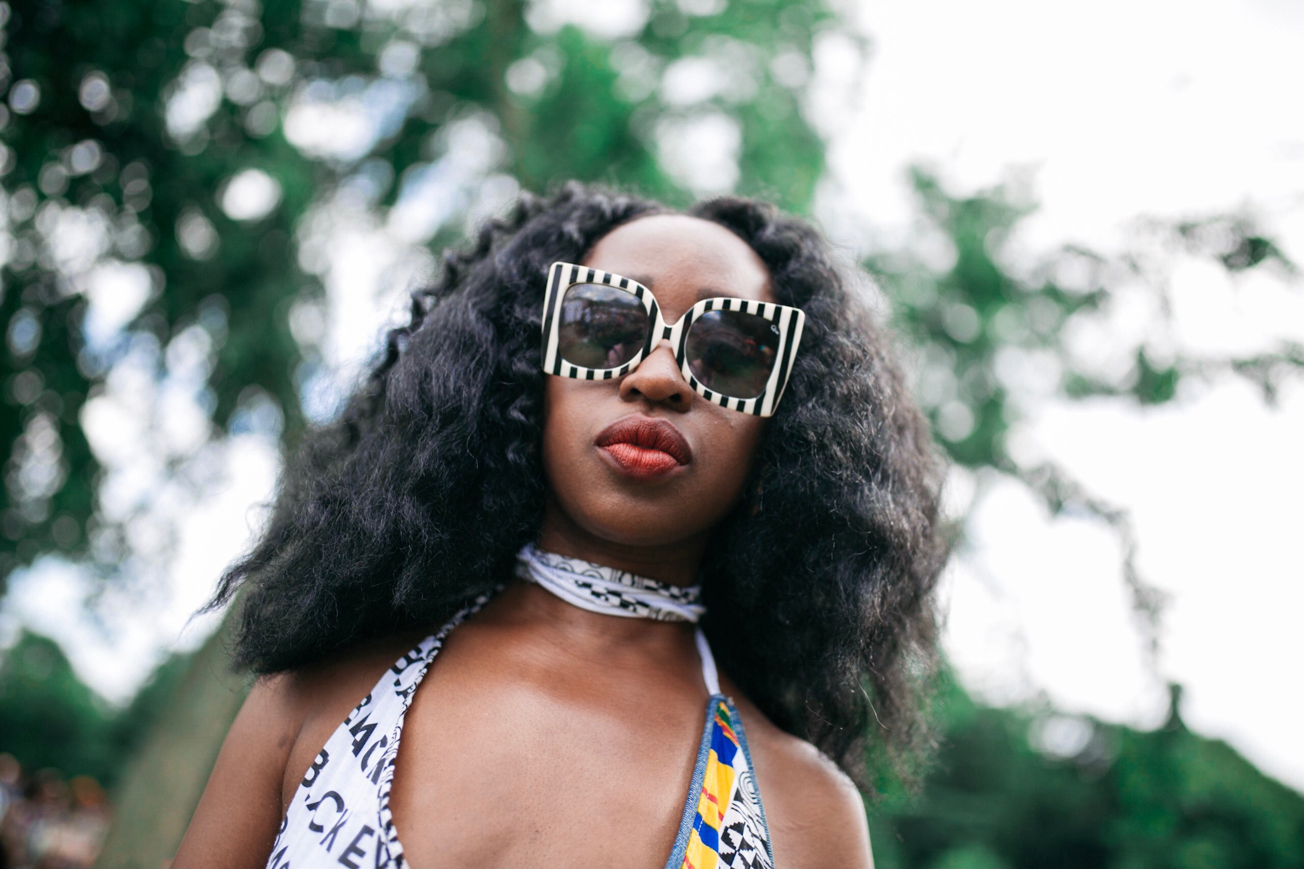 a woman wearing stylish striped sunglasses and lipstick stands before a background of blurry trees, woman in stylish sunglasses 4k, HD Wallpaper