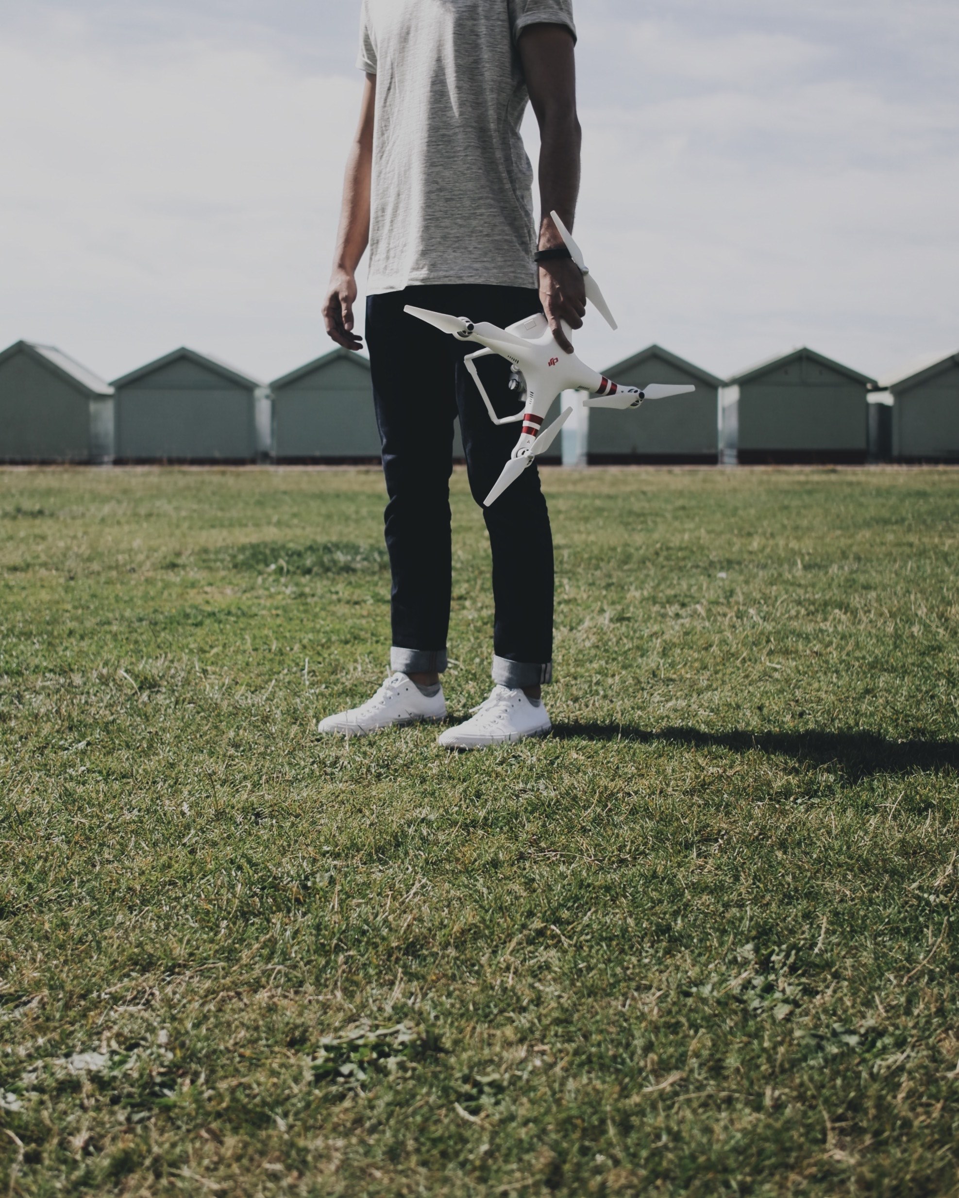 person in black pants holds a drone and remote in a grassy field, person holds drone 4k, Phone HD Wallpaper