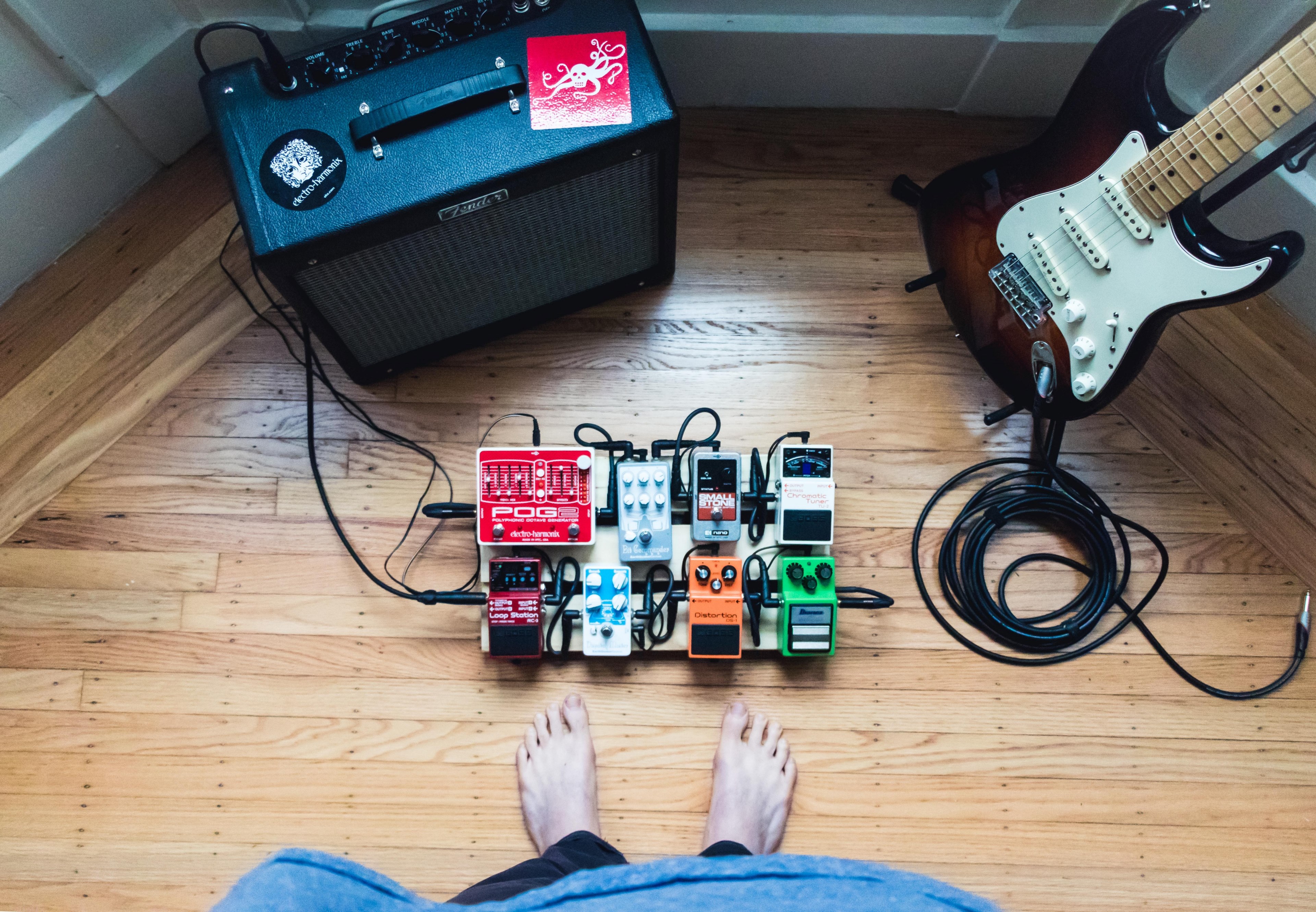 guitar player in sunset district with his feet only showing looks down at his pedal board fender amplifier and stratocaster on a guitar stand, guitar player gear looking 4k, HD Wallpaper