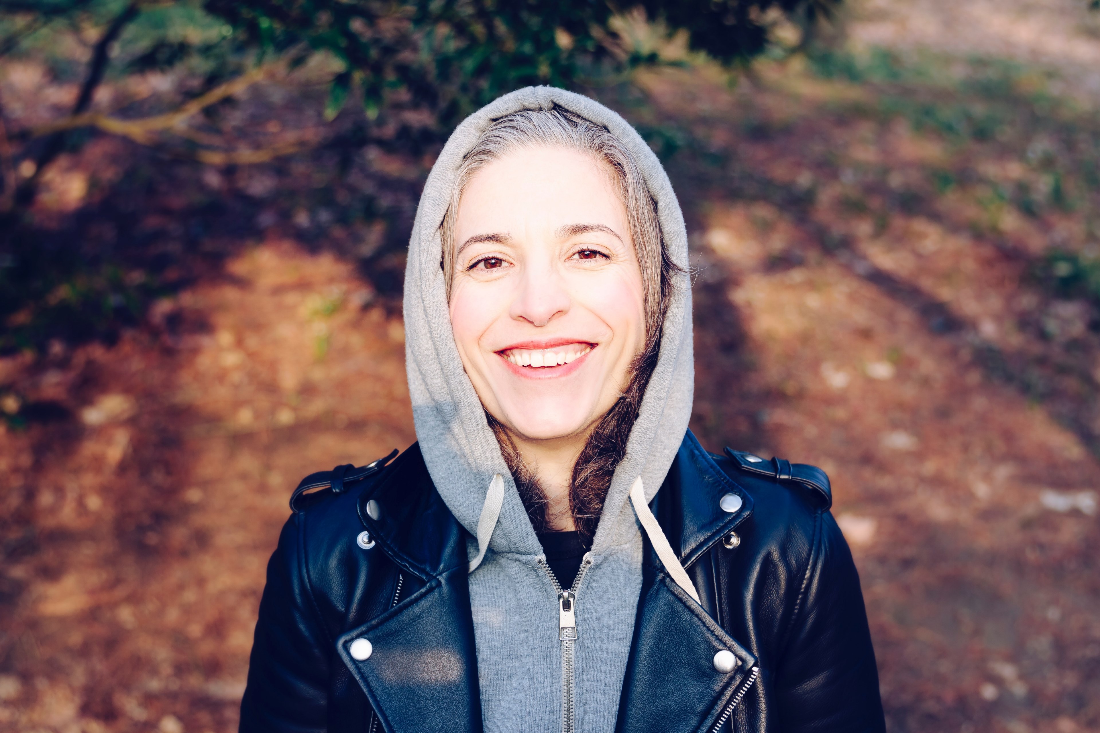 a smiling woman in a gray hooded sweatshirt and leather jacket outside in san sebastin, m 4k, HD Wallpaper