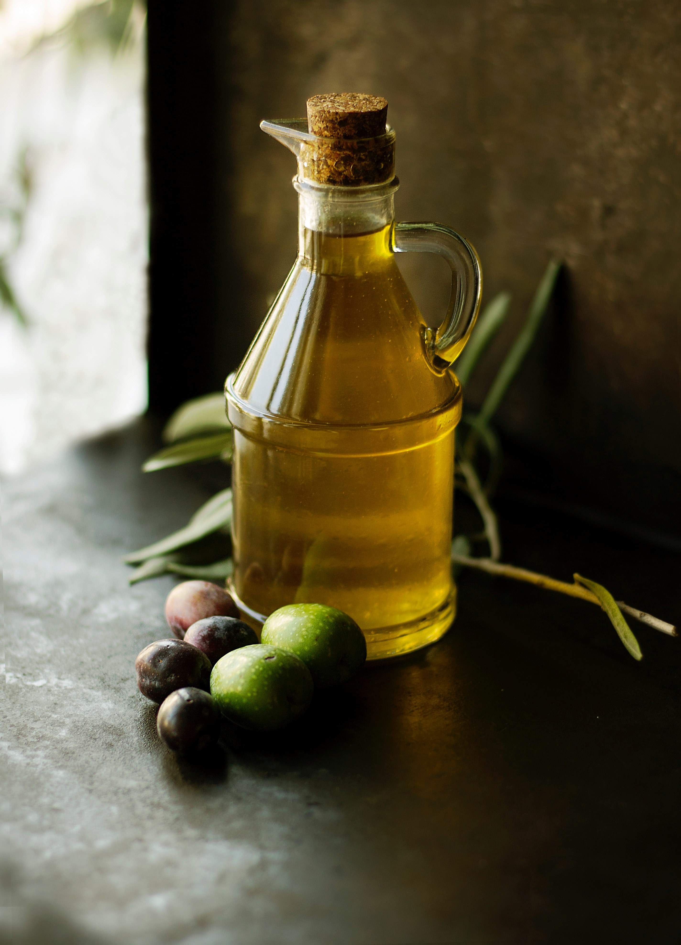 a glass jug of extra virgin olive oil next to some fruit on a table, olive oil 4k, Phone HD Wallpaper
