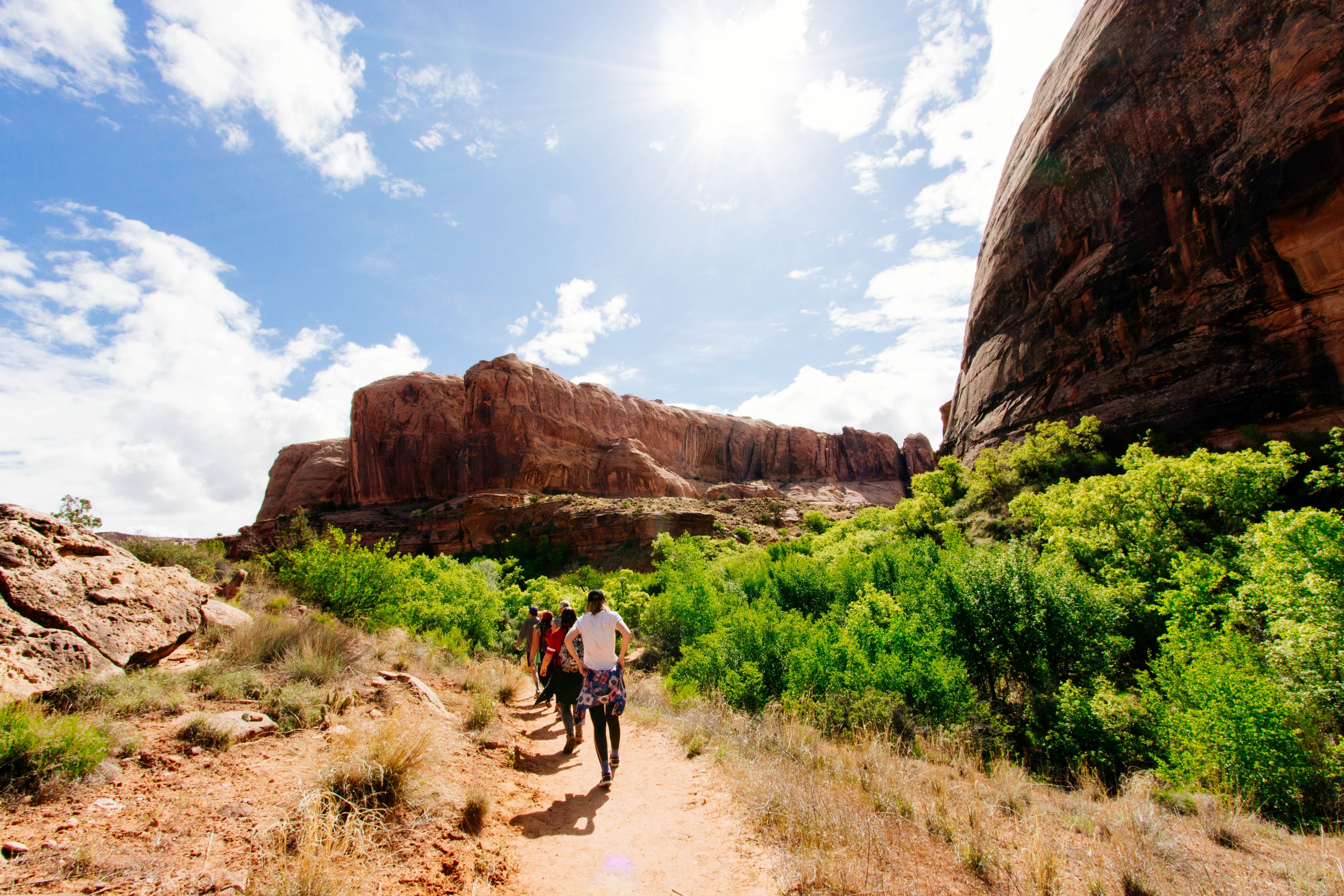 hikers walk along a desert path toward a rocky mountain ridge, group adventures 4k, HD Wallpaper