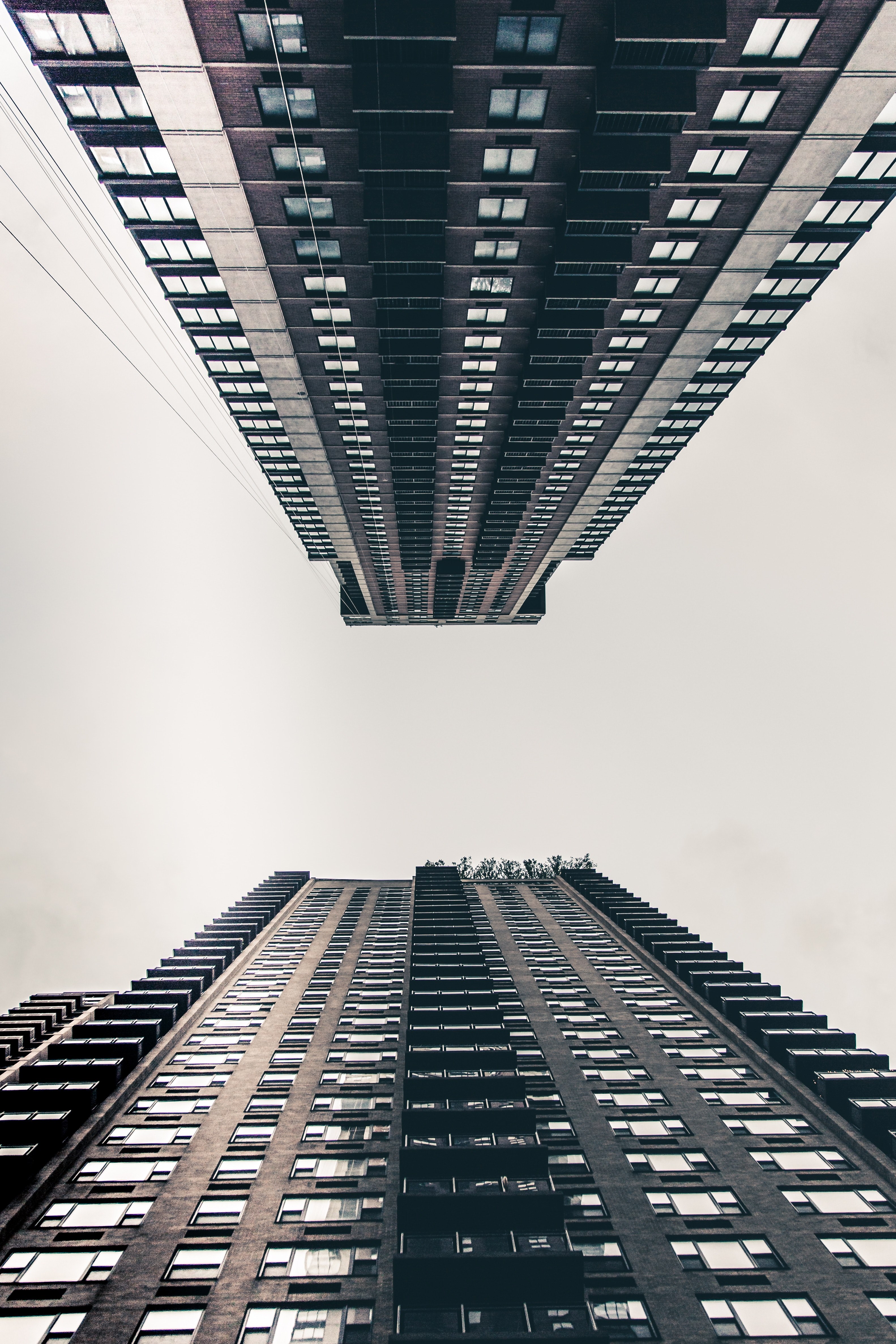 a low angle shot of two tall apartment buildings in new york under a pale white sky, walking in nyc was a nice day for le photos 4k, Phone HD Wallpaper