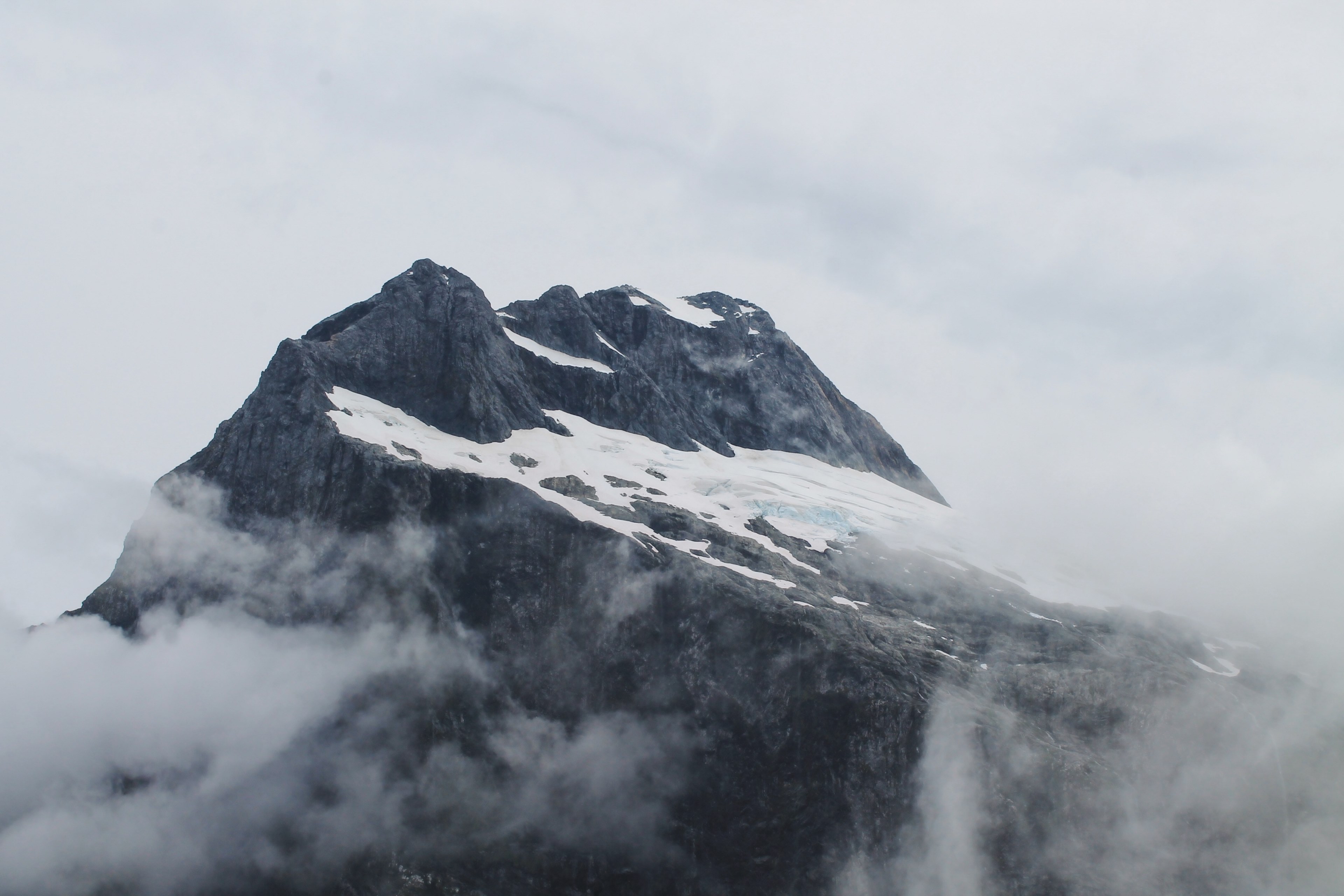the peak of a mountain covered in snow and surrounded by fog, magnificent milford track 4k, HD Wallpaper