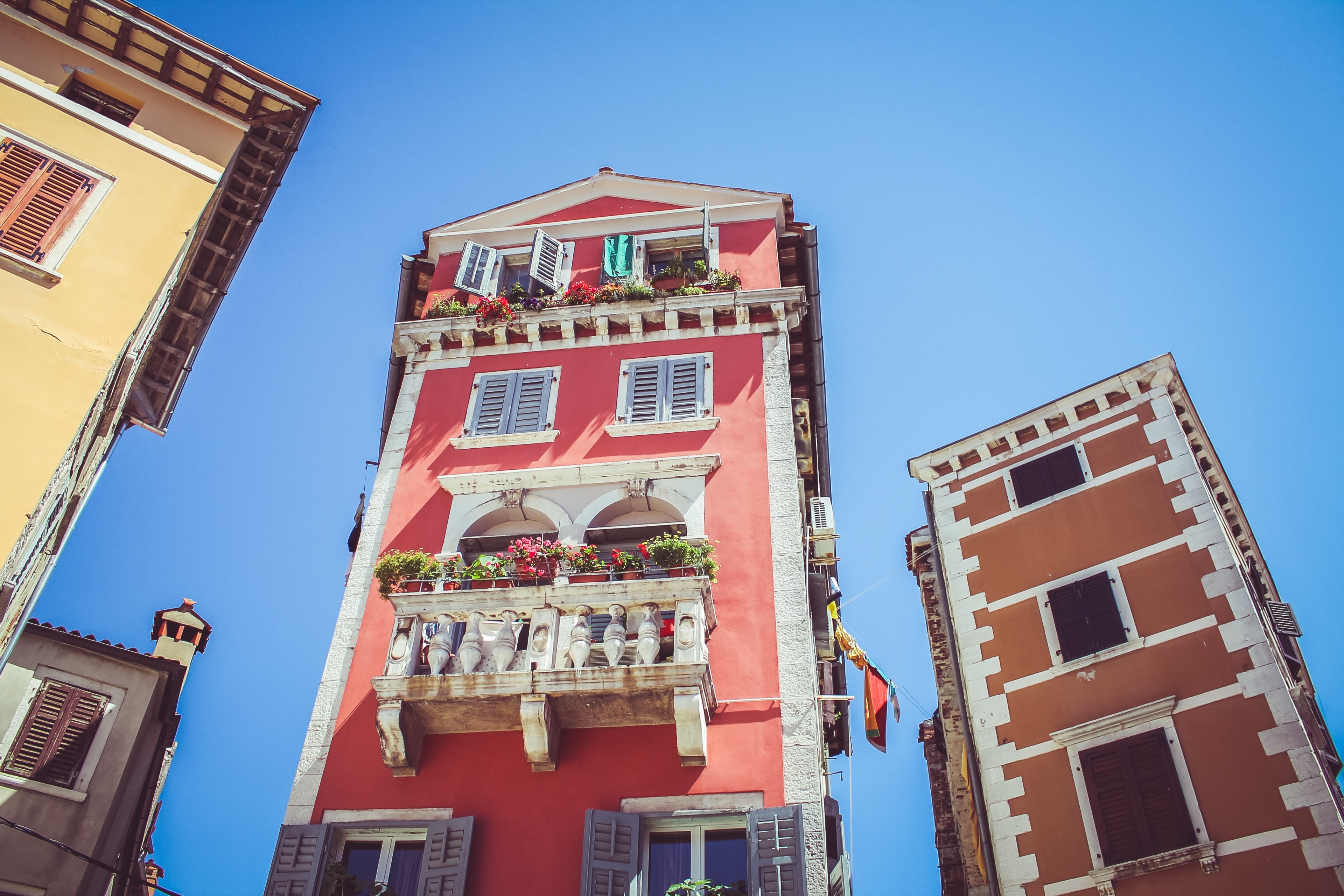 a low angle shot of a tall house with a red facade and a classical balcony, quaint red house 4k, HD Wallpaper