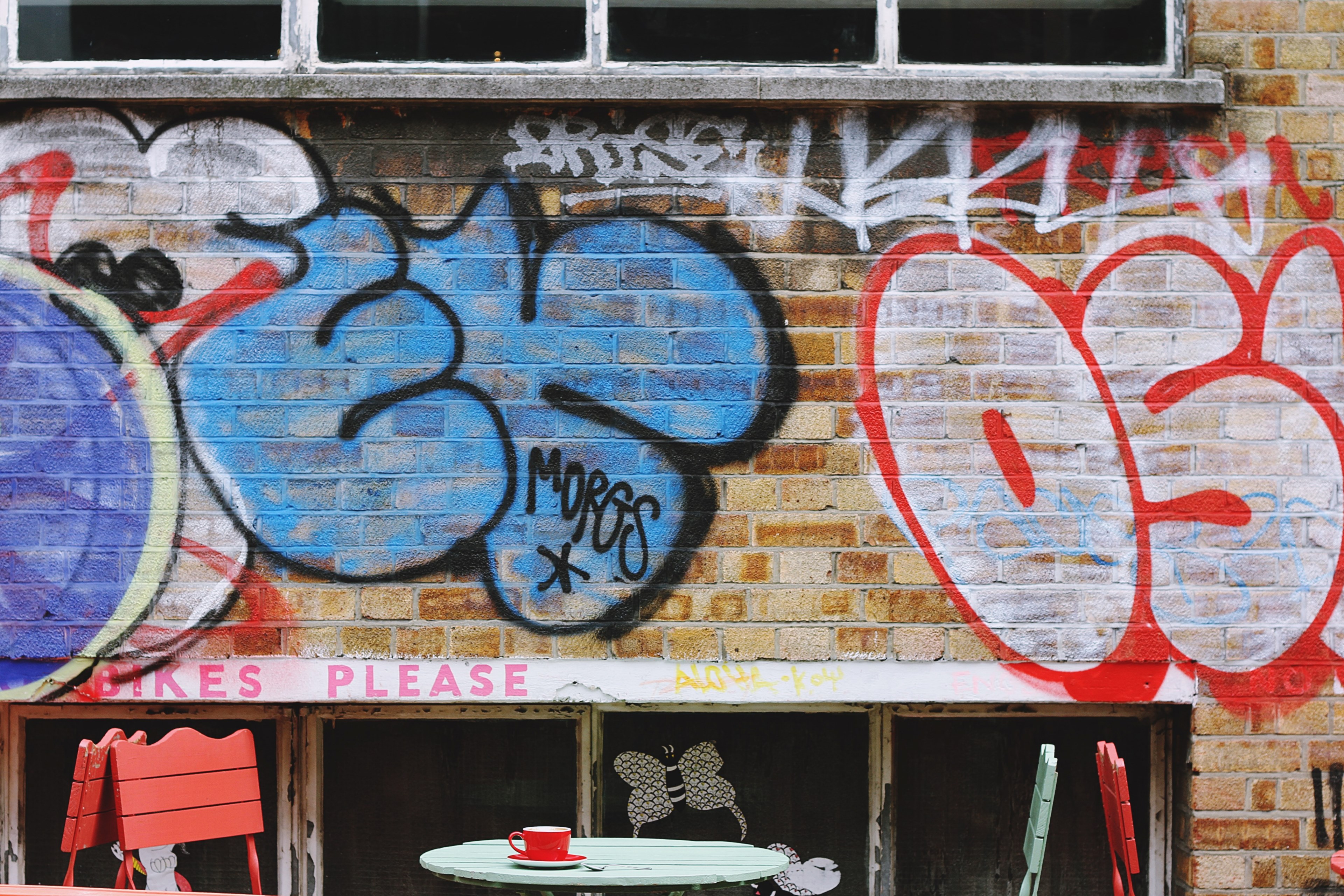 grunge graffiti on brick wall behind colorful tables and chairs in shoreditch, coffee time 4k, HD Wallpaper