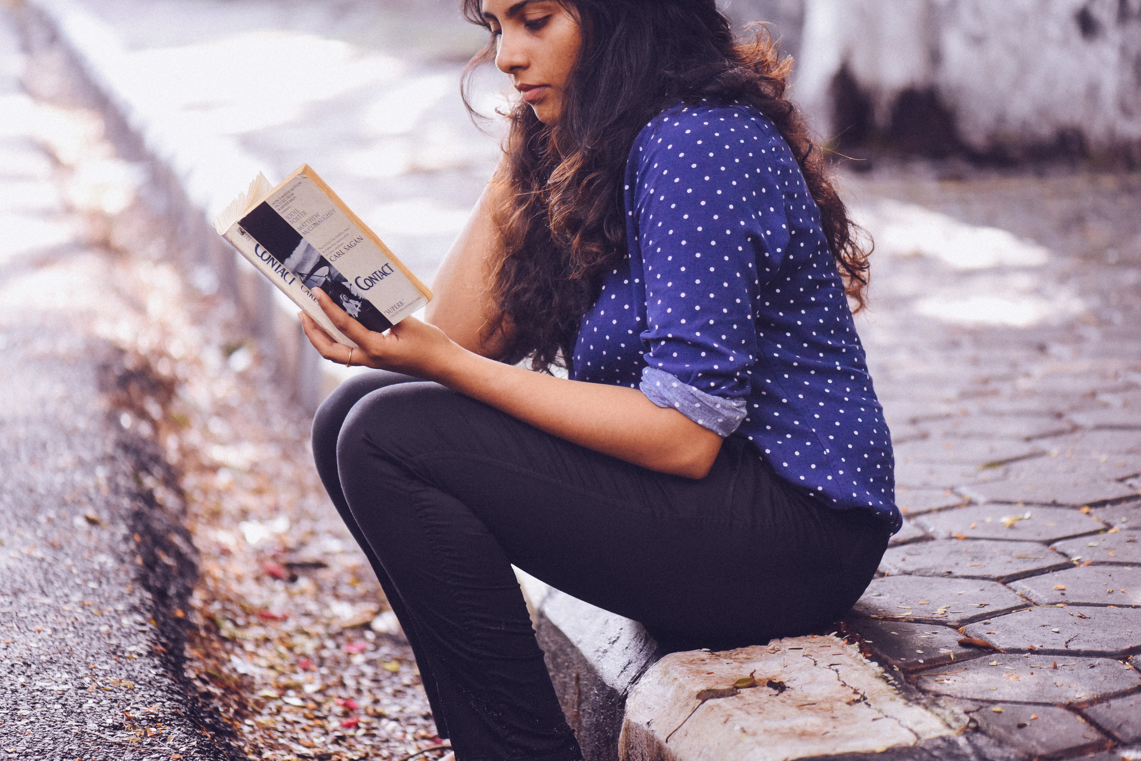 a woman in a polka dotted blouse sits on a curb reading a book, let solitude silence amp the summer rain soak in_ 4k, HD Wallpaper