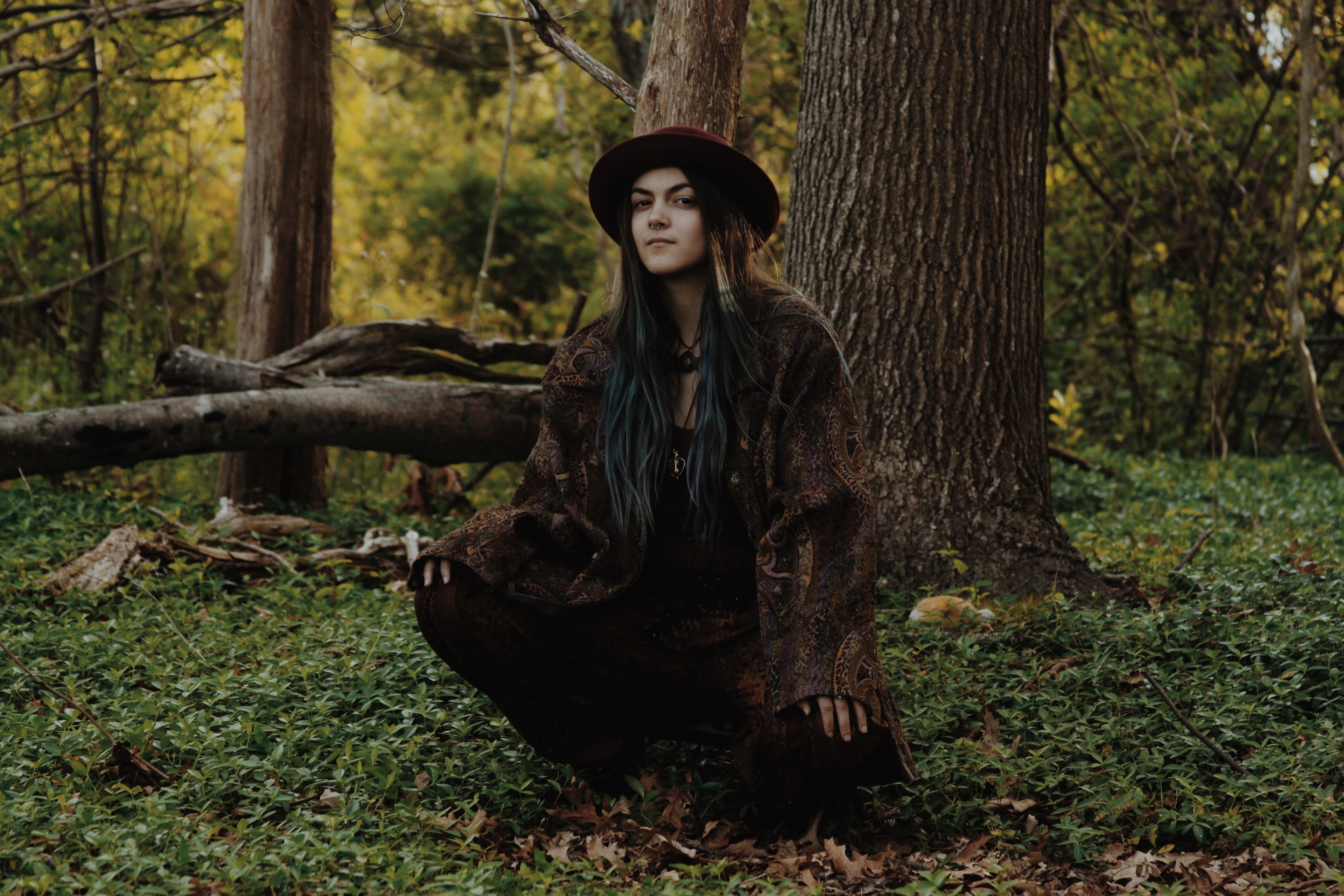 a young bohemian woman crouching under a tree in a forest, bohemian woman in the woods 4k, HD Wallpaper