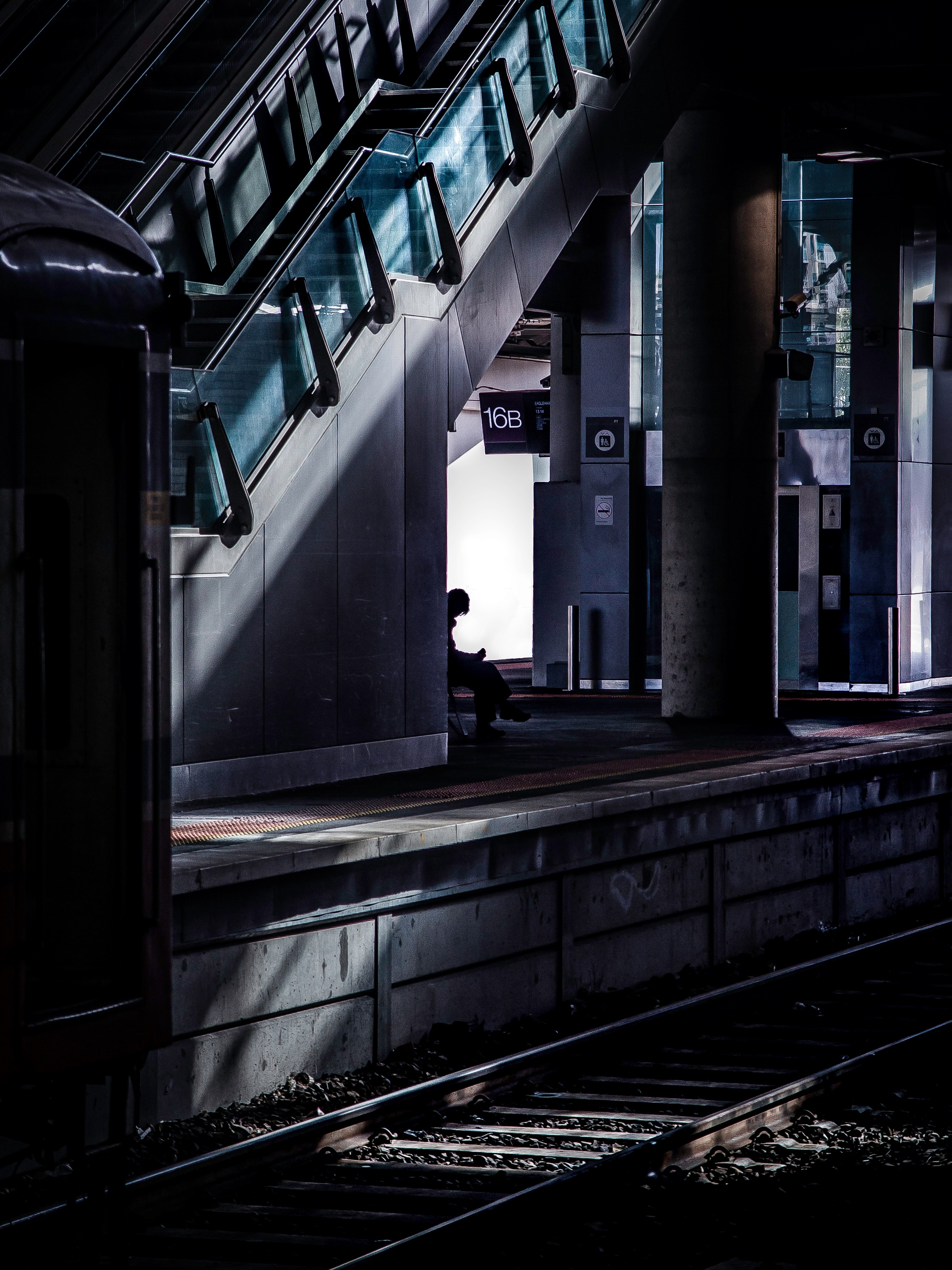 a dark shot of the silhouette of a lone passenger waiting for a train at a railway platform, lone commuter at a platform 4k, Phone HD Wallpaper