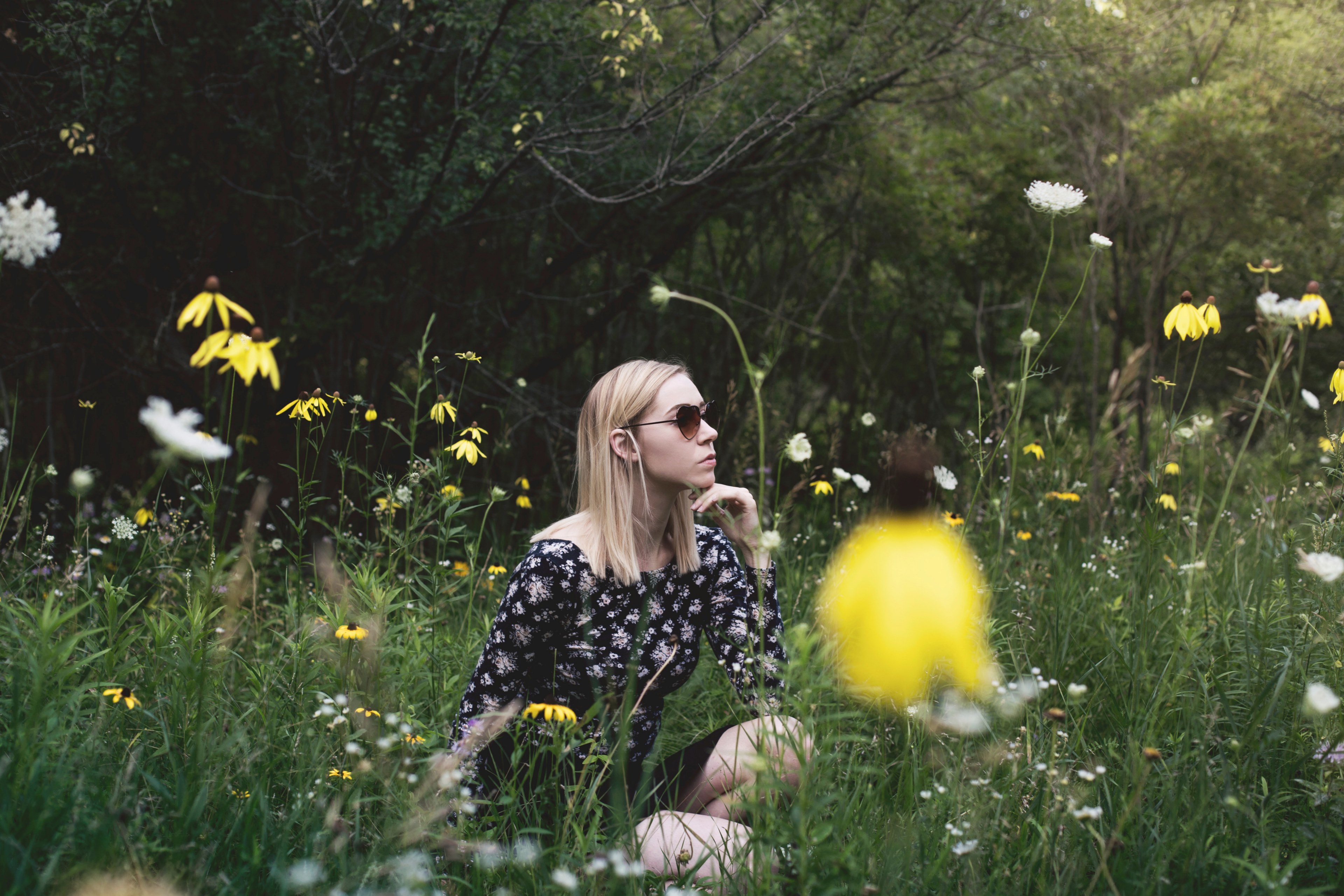 a woman in sunglasses sitting among white and yellow flowers in a meadow, woman in sunglasses in meadow 4k, HD Wallpaper