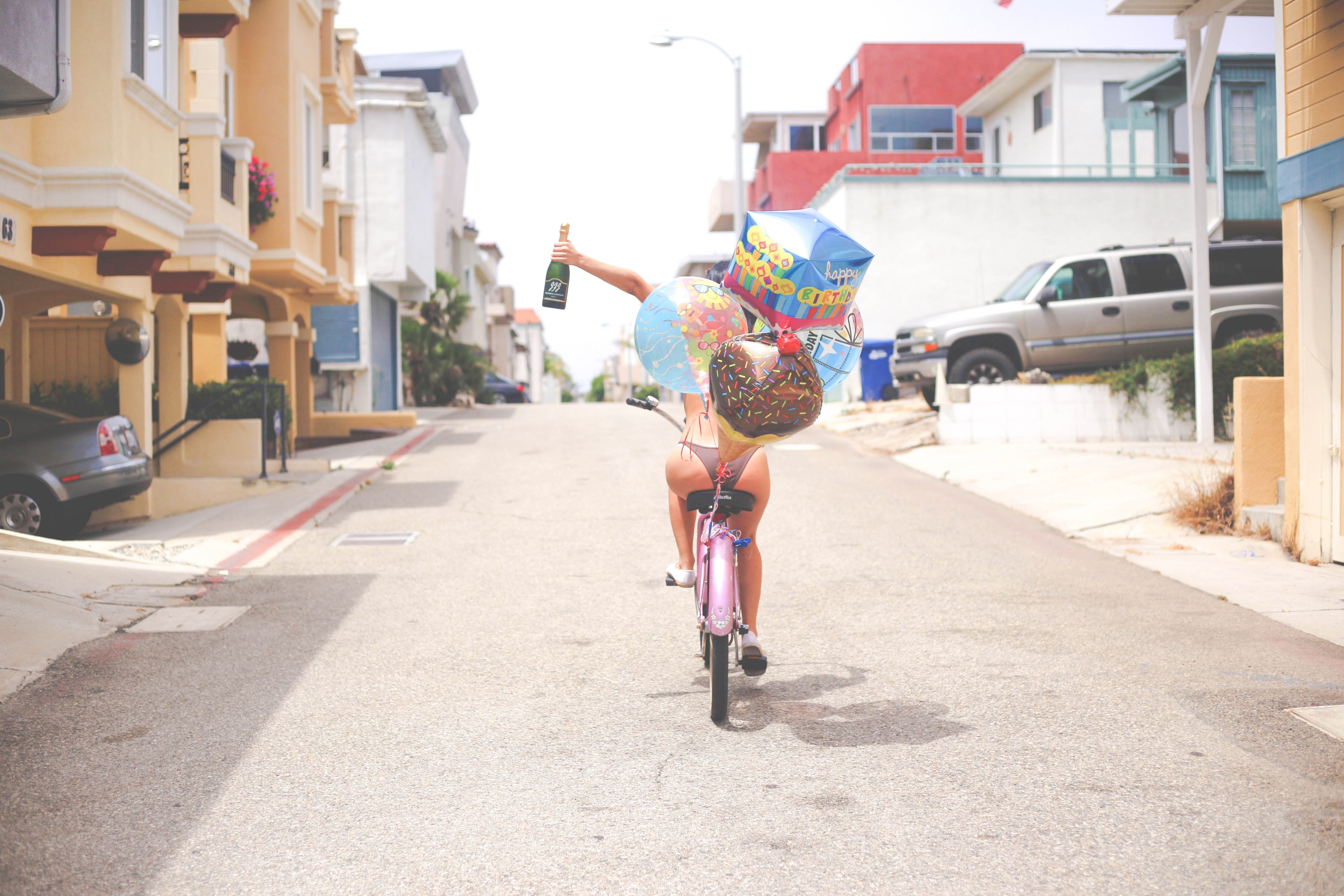 woman driving a balloon decorated bicycle celebrating and holding a champagne bottle on the street at hermosa beach, birthday girl on a bike 2 4k, HD Wallpaper