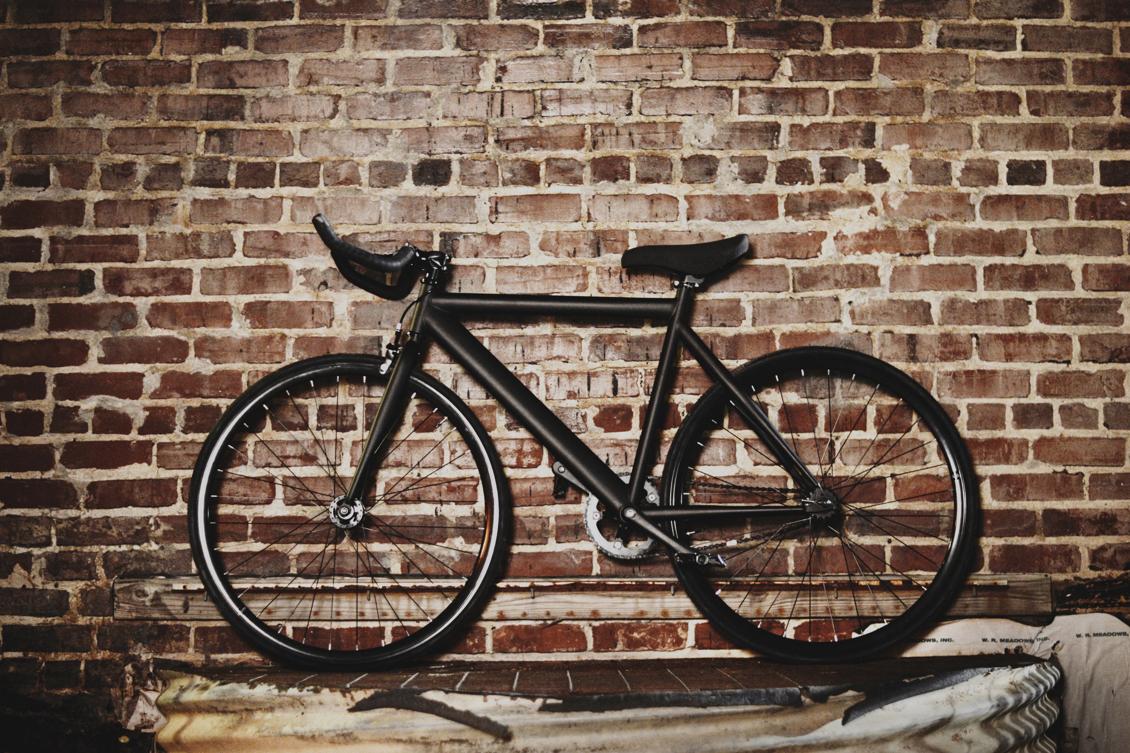 black bike sits against dark brick wall, bike against brick wall 4k, HD Wallpaper