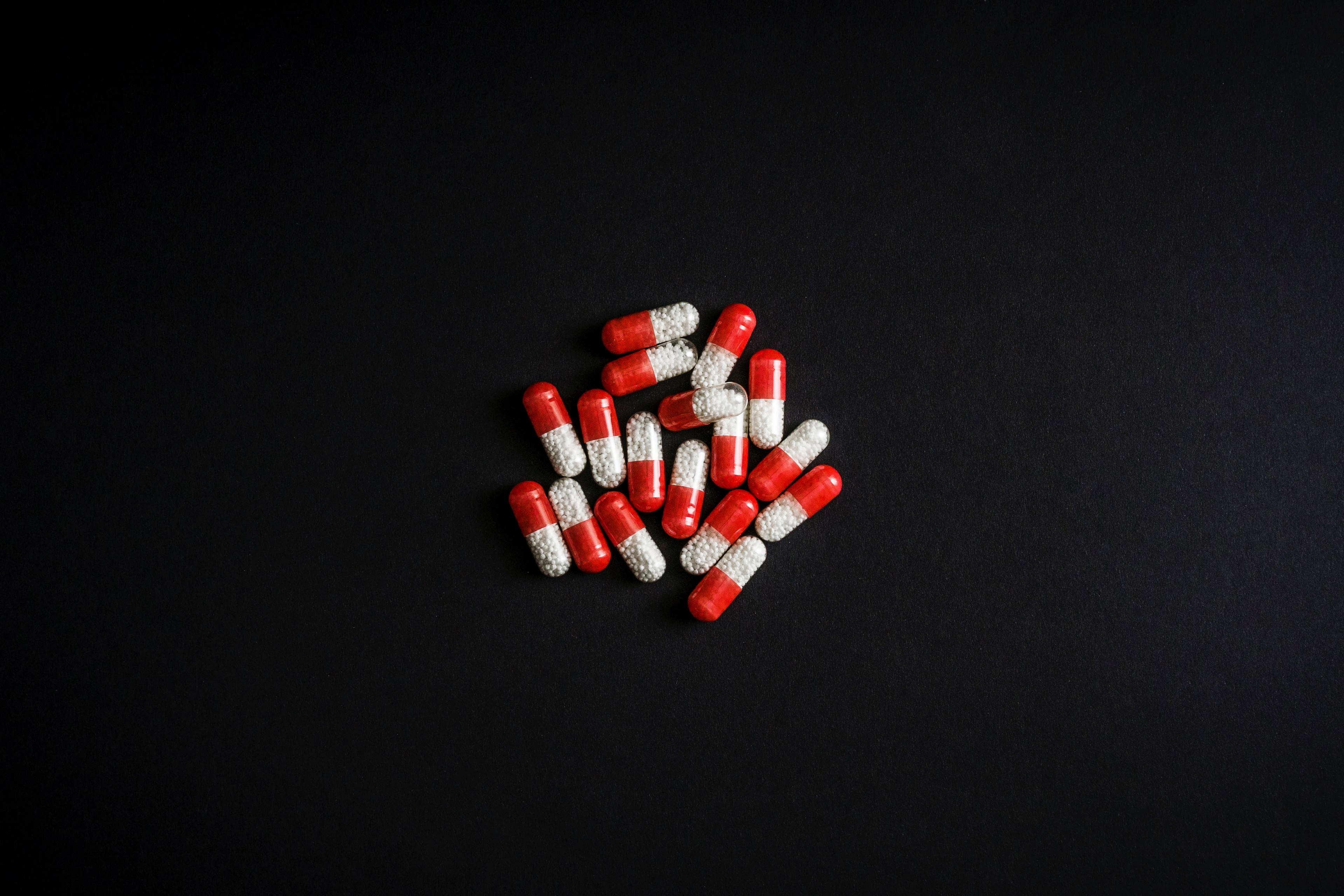 a pile of red and white capsules with a black background, _drugs 4k, HD Wallpaper