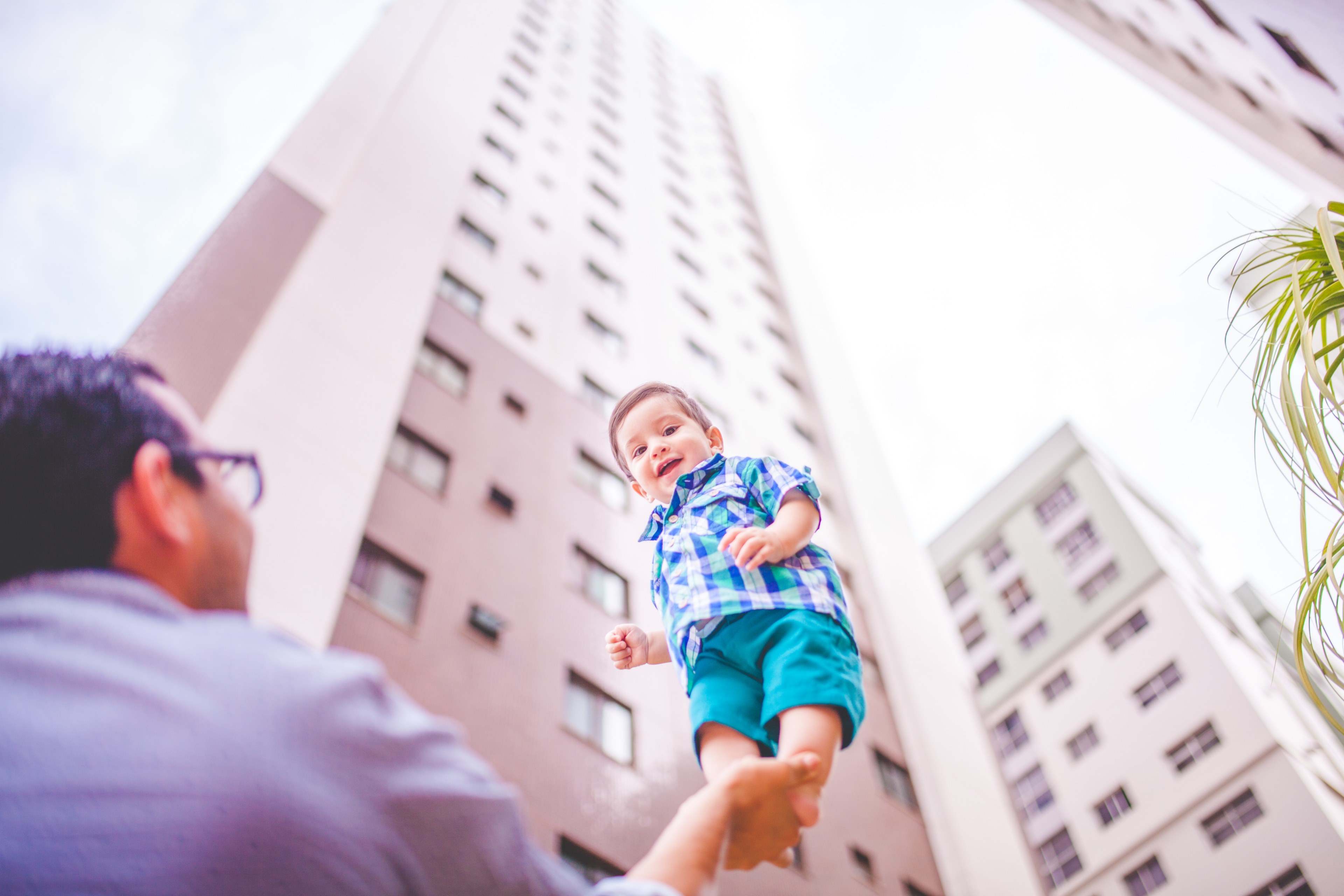 a man holds a child on the palm of his hand in front of a skyscraper, father and son courage 4k, HD Wallpaper