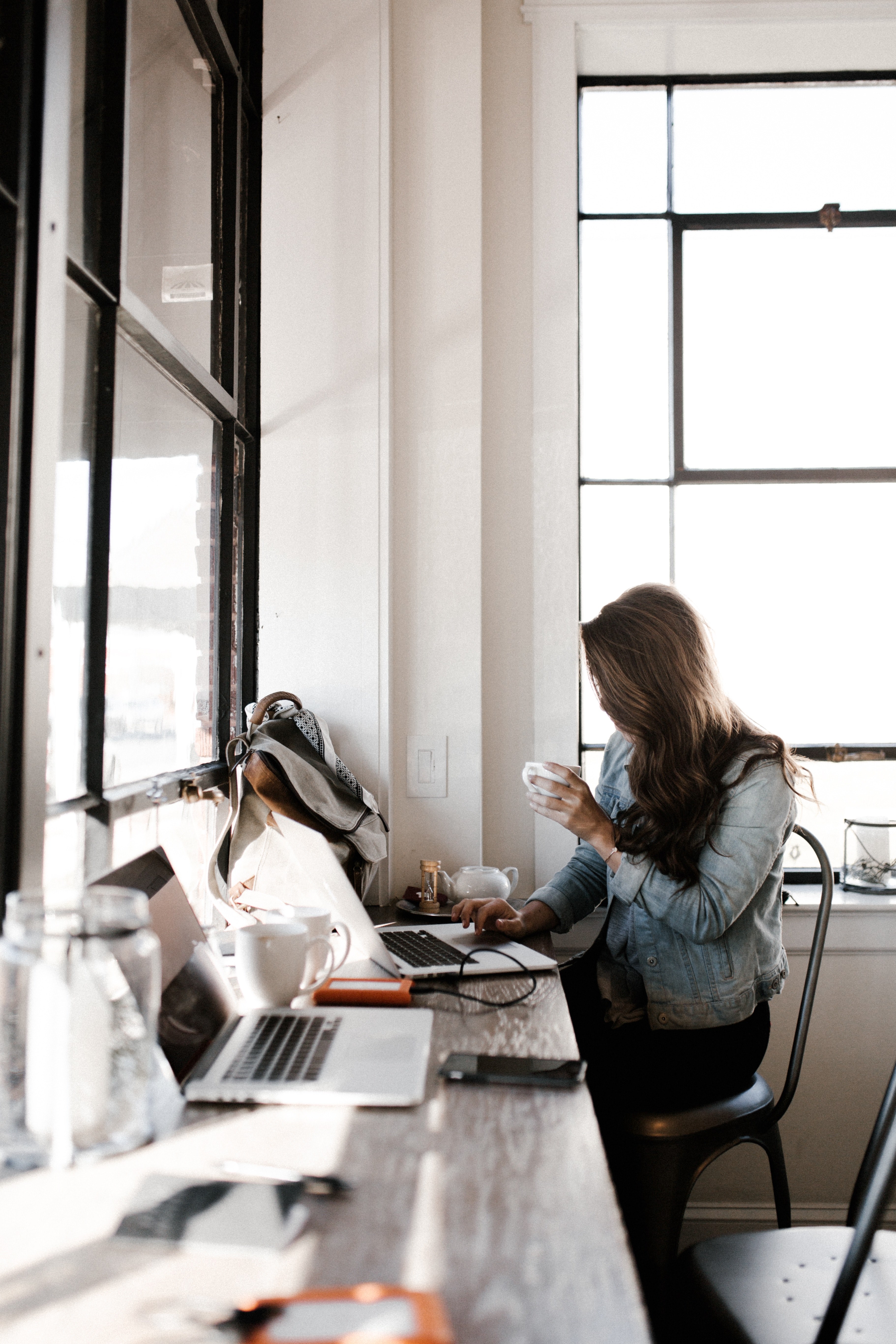 a woman holding a white cup while working on a laptop near a window, follow your passion 4k, Phone HD Wallpaper