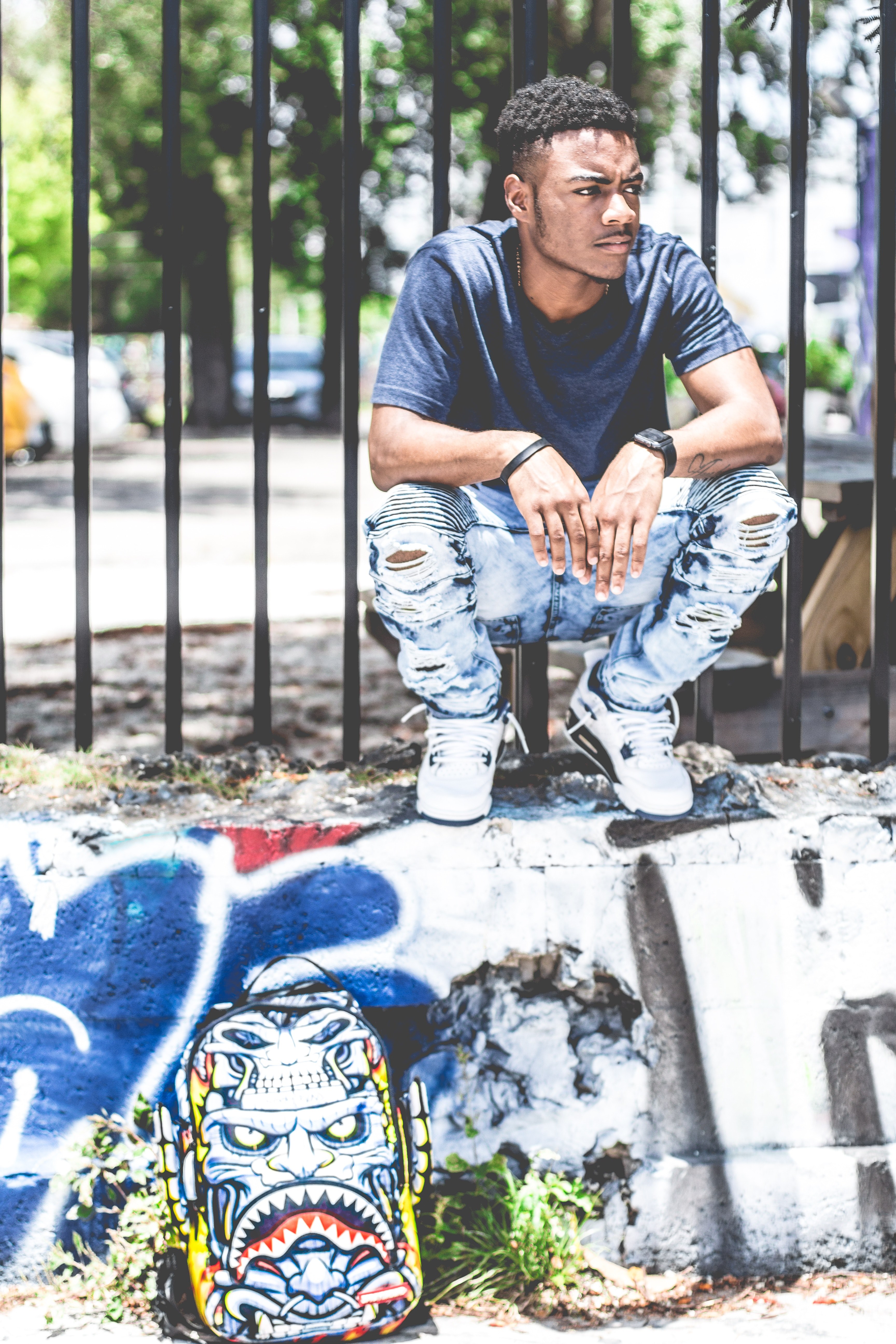 man wearing urban clothing and watch sitting on a graffitied wall, city living 4k, Phone HD Wallpaper