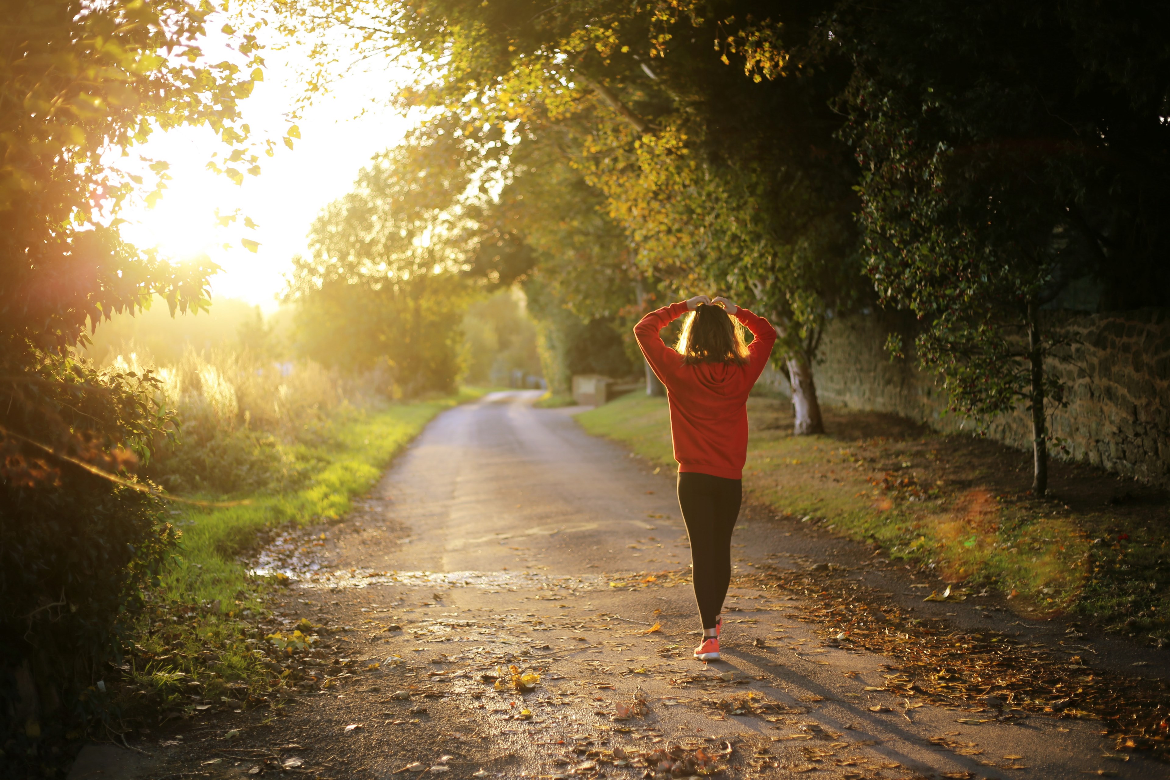 a woman wearing a red sweater and sneakers walking with her hands on top of her head down a path during fall in west sussex, morning jog in the countryside 4k, HD Wallpaper