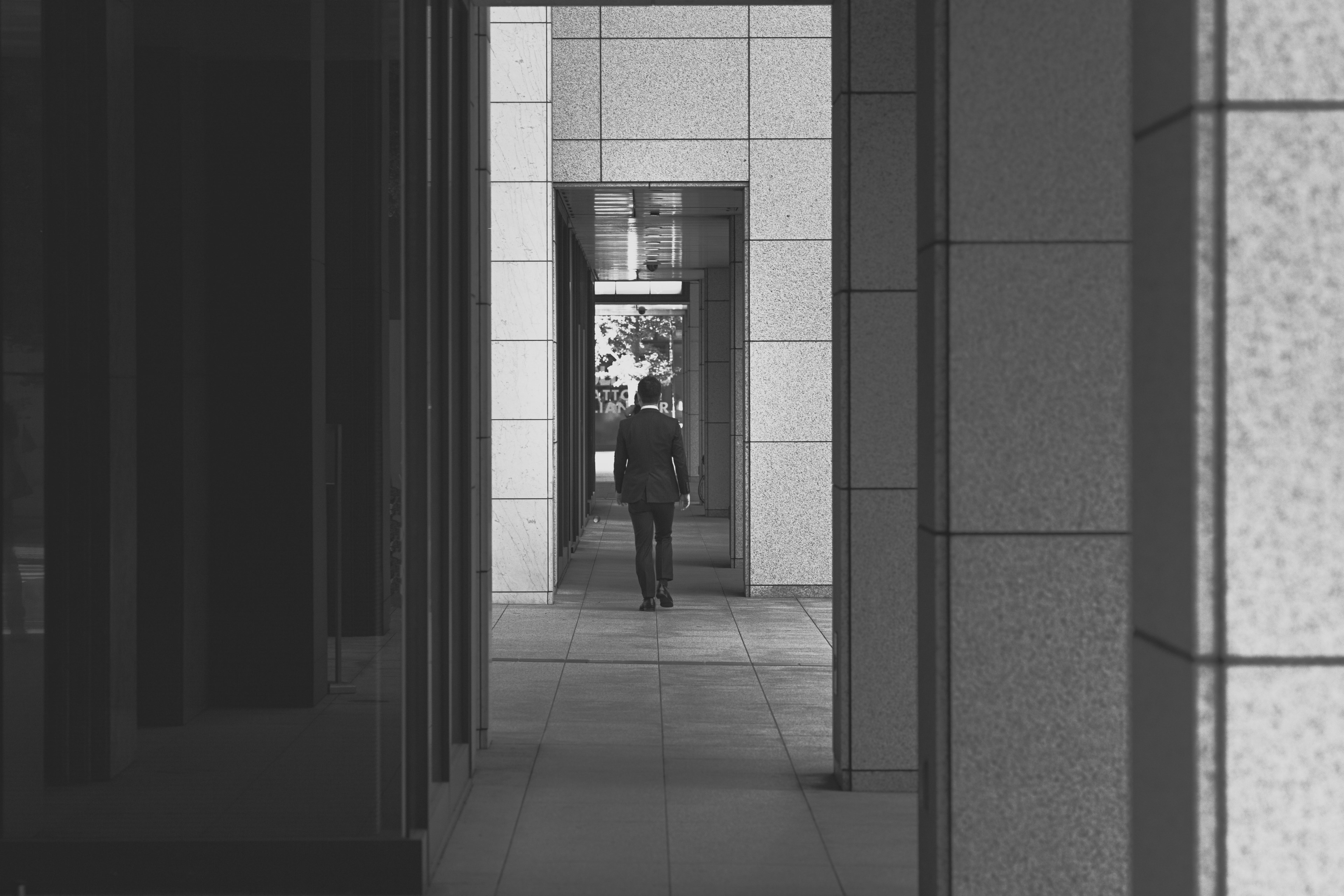 black and white shot of person walking through outdoor corporate building hallway in suit, outdoor corporate hallway 4k, HD Wallpaper