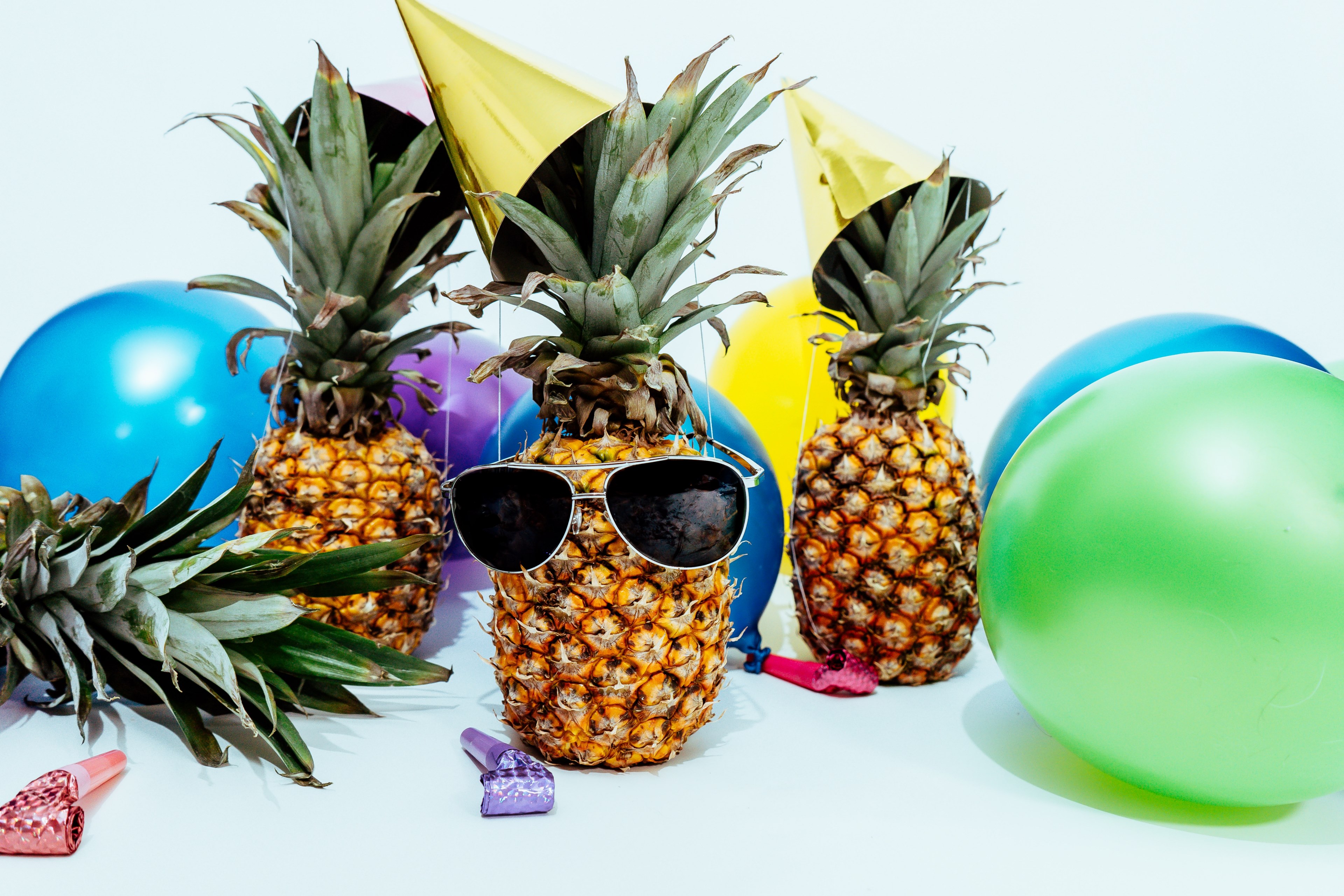 three pineapples wearing party hats and one wearing sunglasses surrounded by colourful balloons and party items by scott webb photography, celebration 4k, HD Wallpaper
