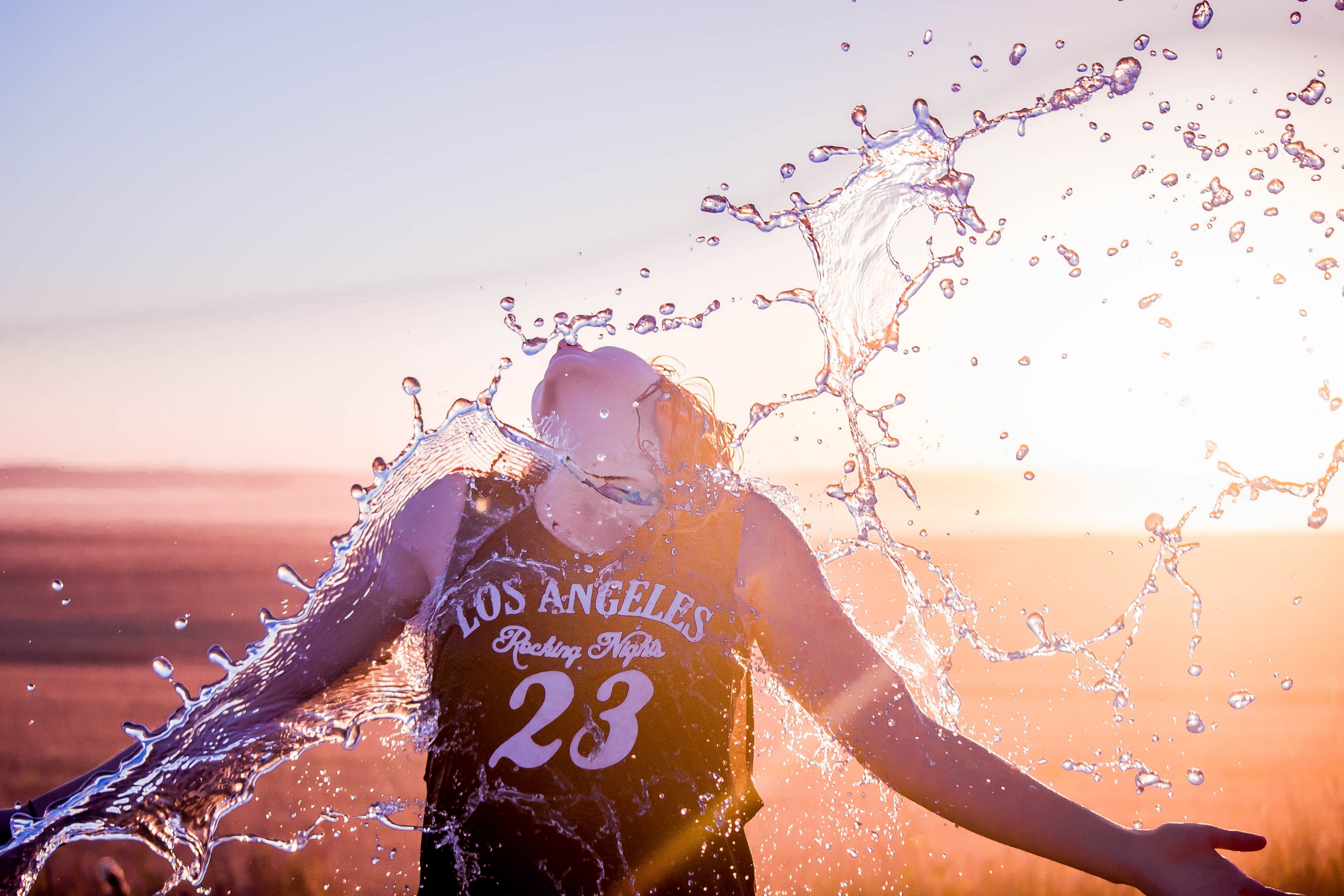 female wearing a los angeles jersey being splashed with water under the sunset in alberta, water refreshes athlete 4k, HD Wallpaper