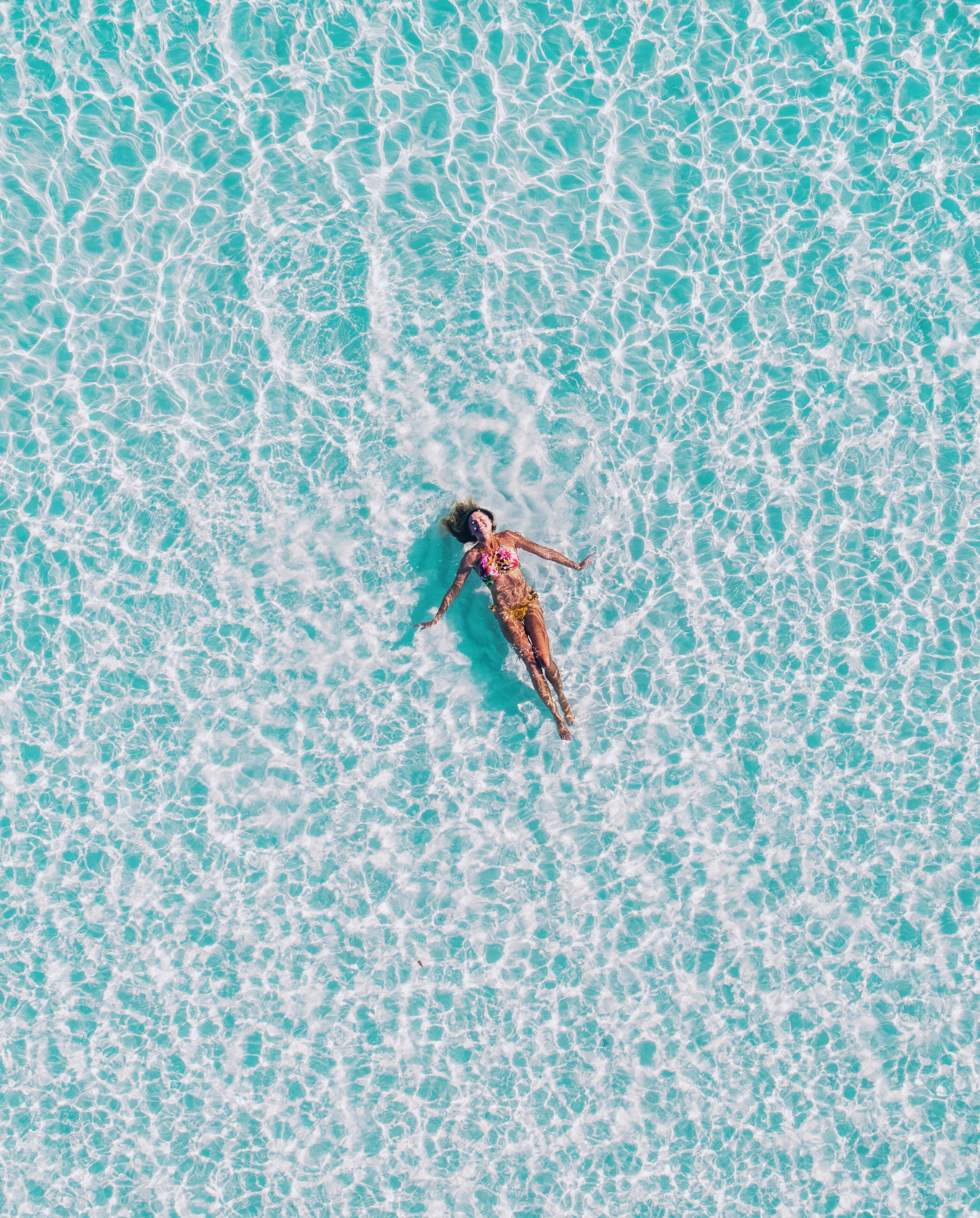 a top view of a woman in a bikini swimming on her back in clear ocean water, lost in the turquoise 4k, Phone HD Wallpaper