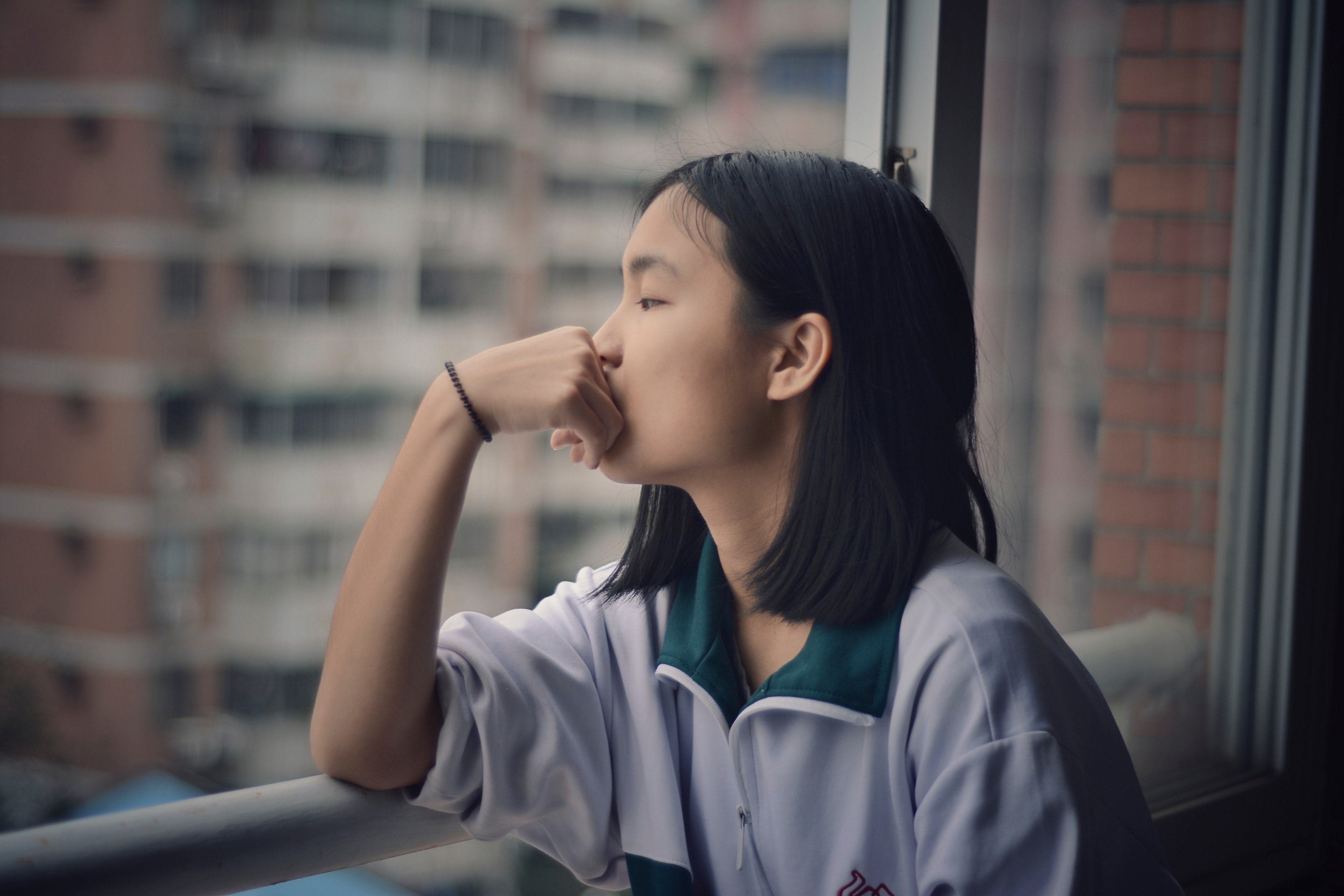 a teenager looks out the window with a hand on mouth and elbows on the railing, _teenage girl window railing 4k, HD Wallpaper
