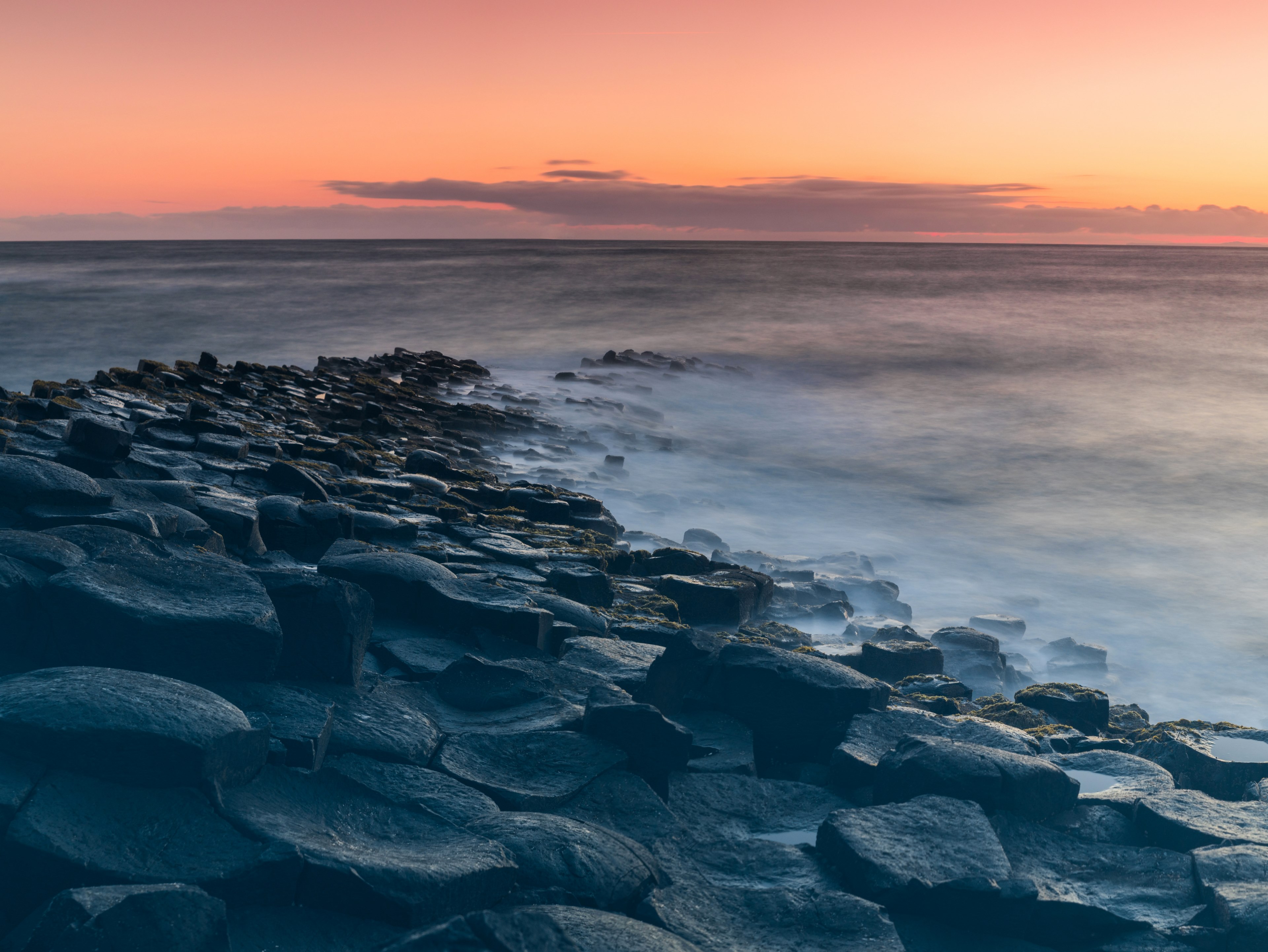 the giants causeway with a misty sea breaking on the rocks and a pink sky illuminating the horizon during dawn or dusk, the giants causeway and misty sea during twilight 4k, HD Wallpaper