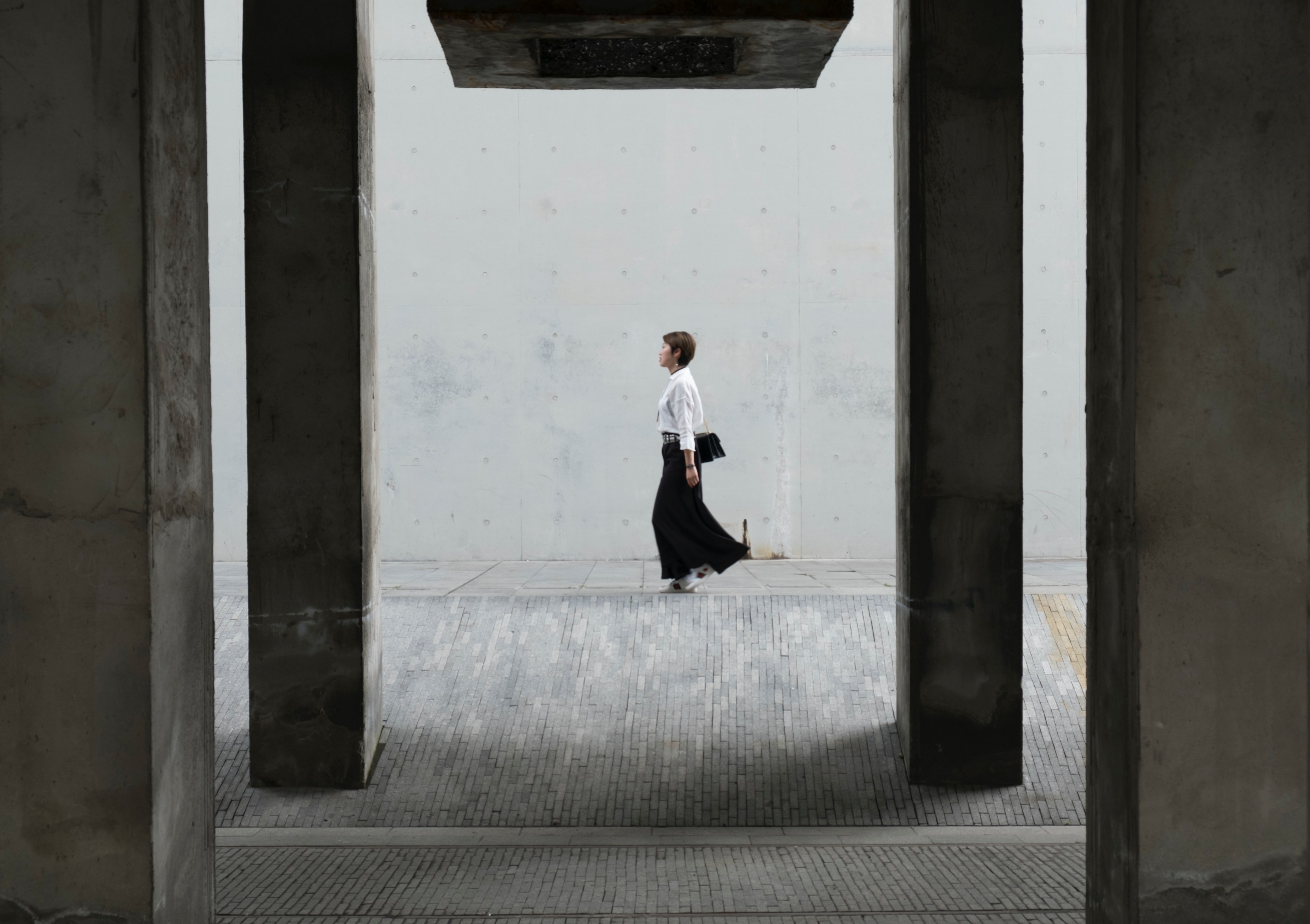 a woman in a black skirt walking on a sidewalk near a wall, architectural frames 4k, HD Wallpaper