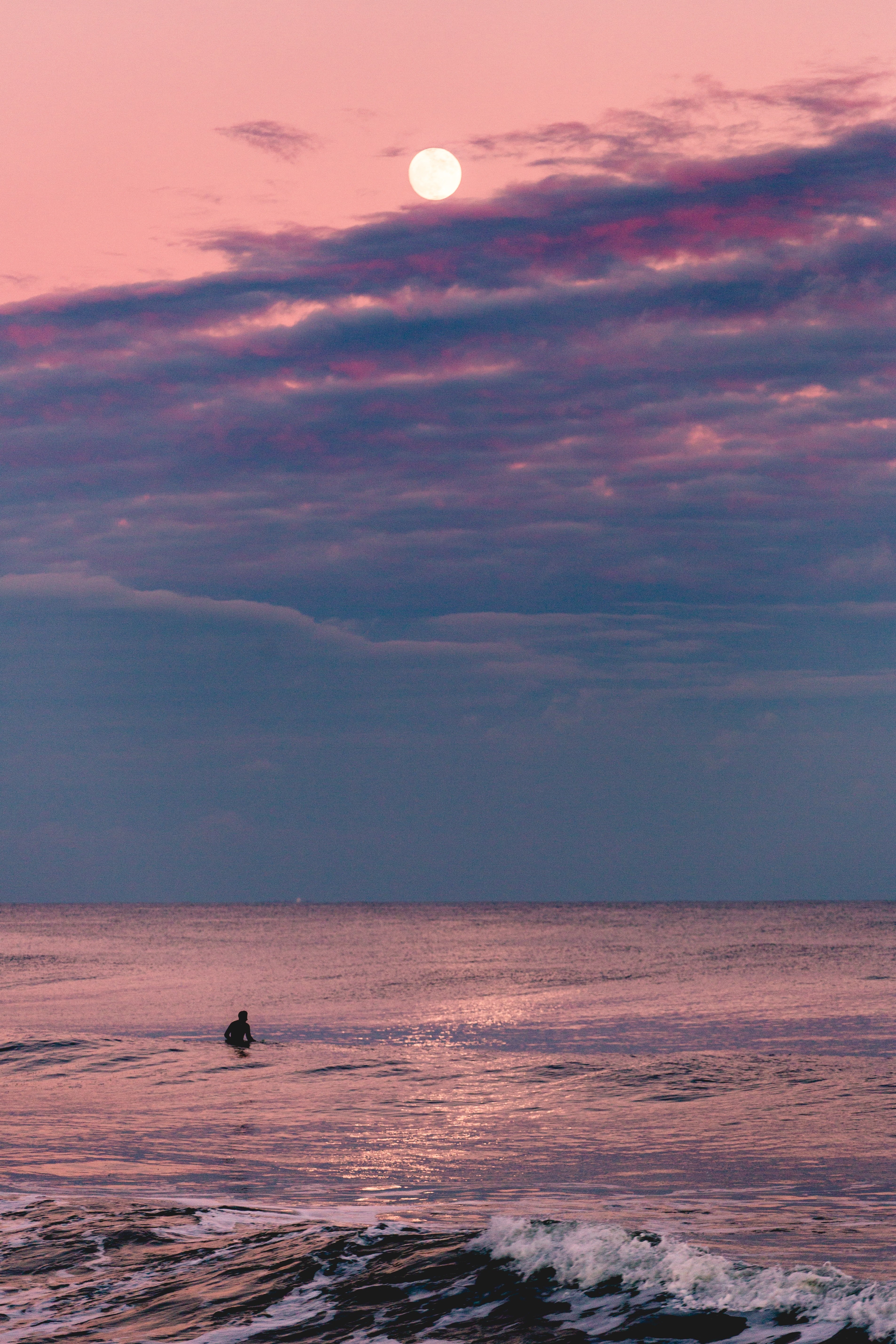 a surfer at avon by the sea at dusk with a full moon above on a pink cloudy sky, not afraid of sharks 4k, Phone HD Wallpaper