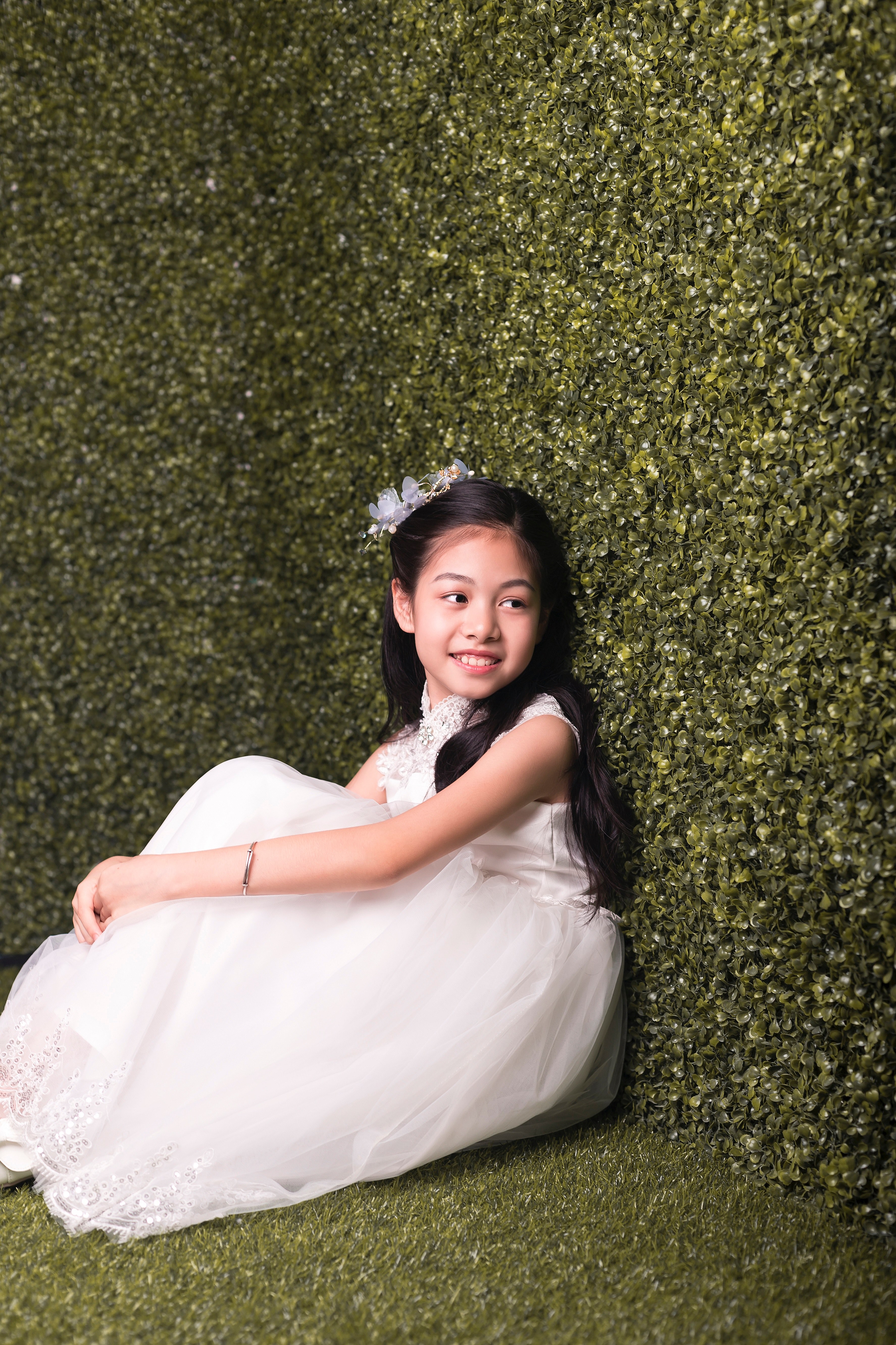 a smiling child in a white dress sits against a hedge in tancun, pretty girl 4k, Phone HD Wallpaper
