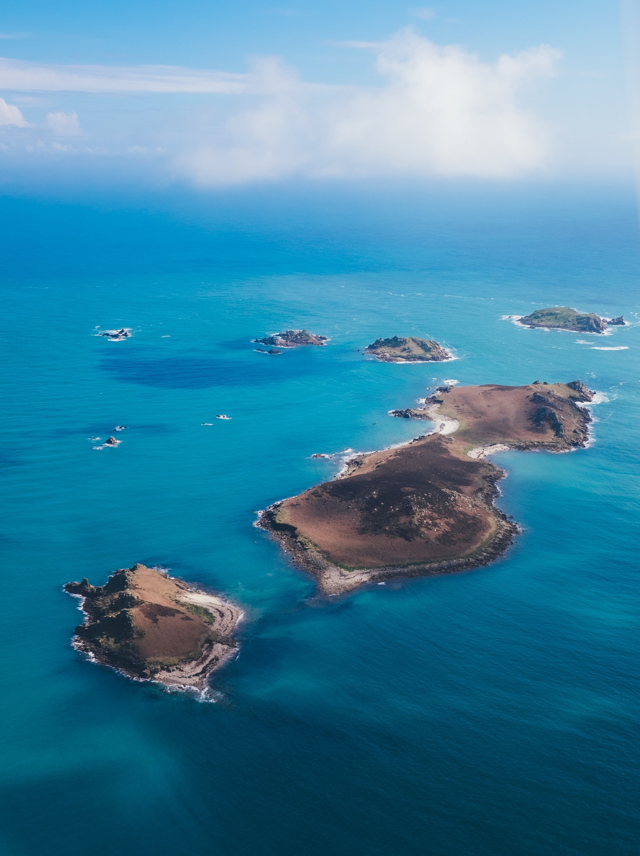 drone view of the isles of scilly poking out of clear blue water on a sunny day, island life 4k, Phone HD Wallpaper