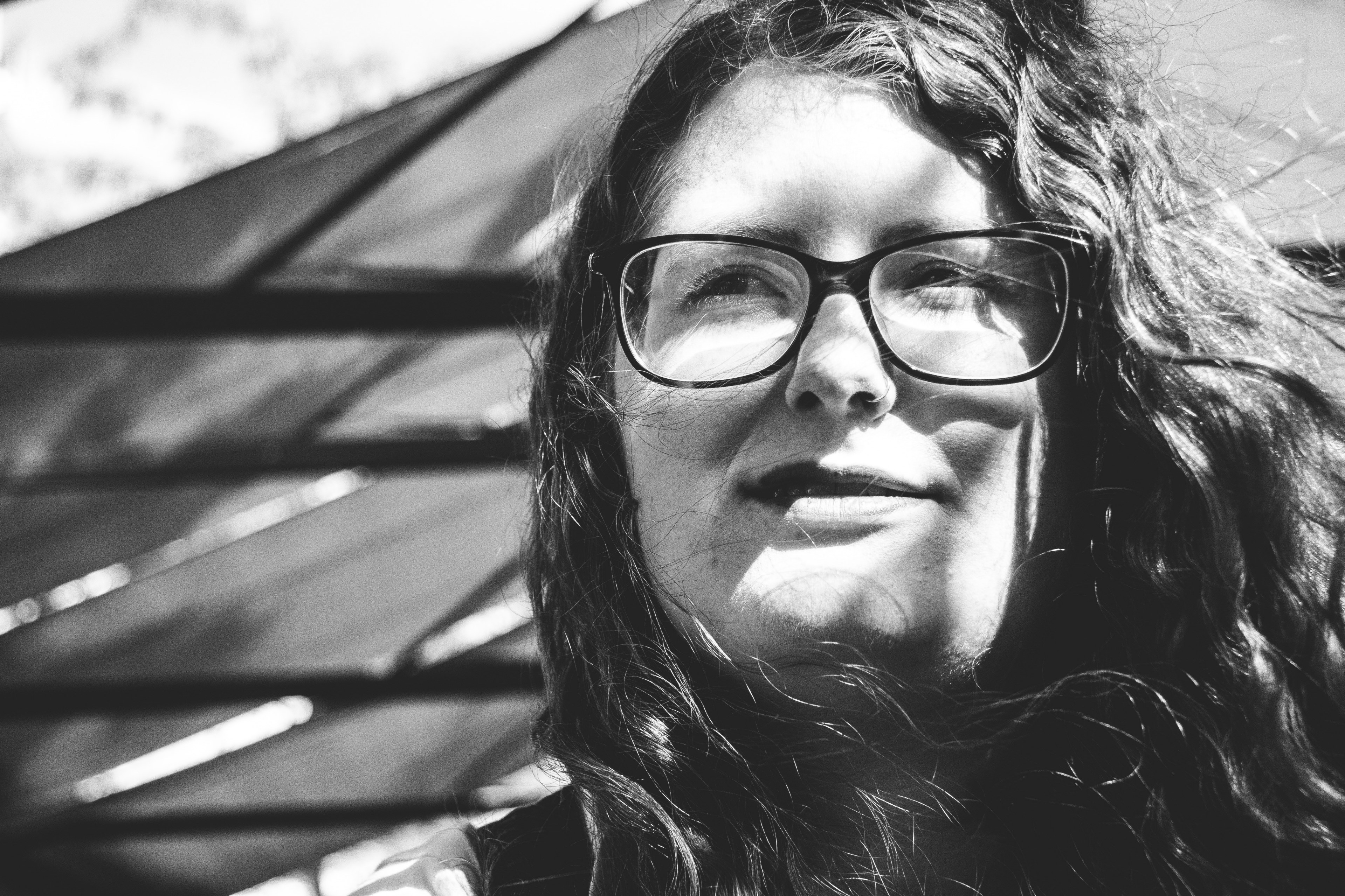 black and white photograph of a woman with glasses and long hair smiling into the distance, _woman in glasses smiling 4k, HD Wallpaper