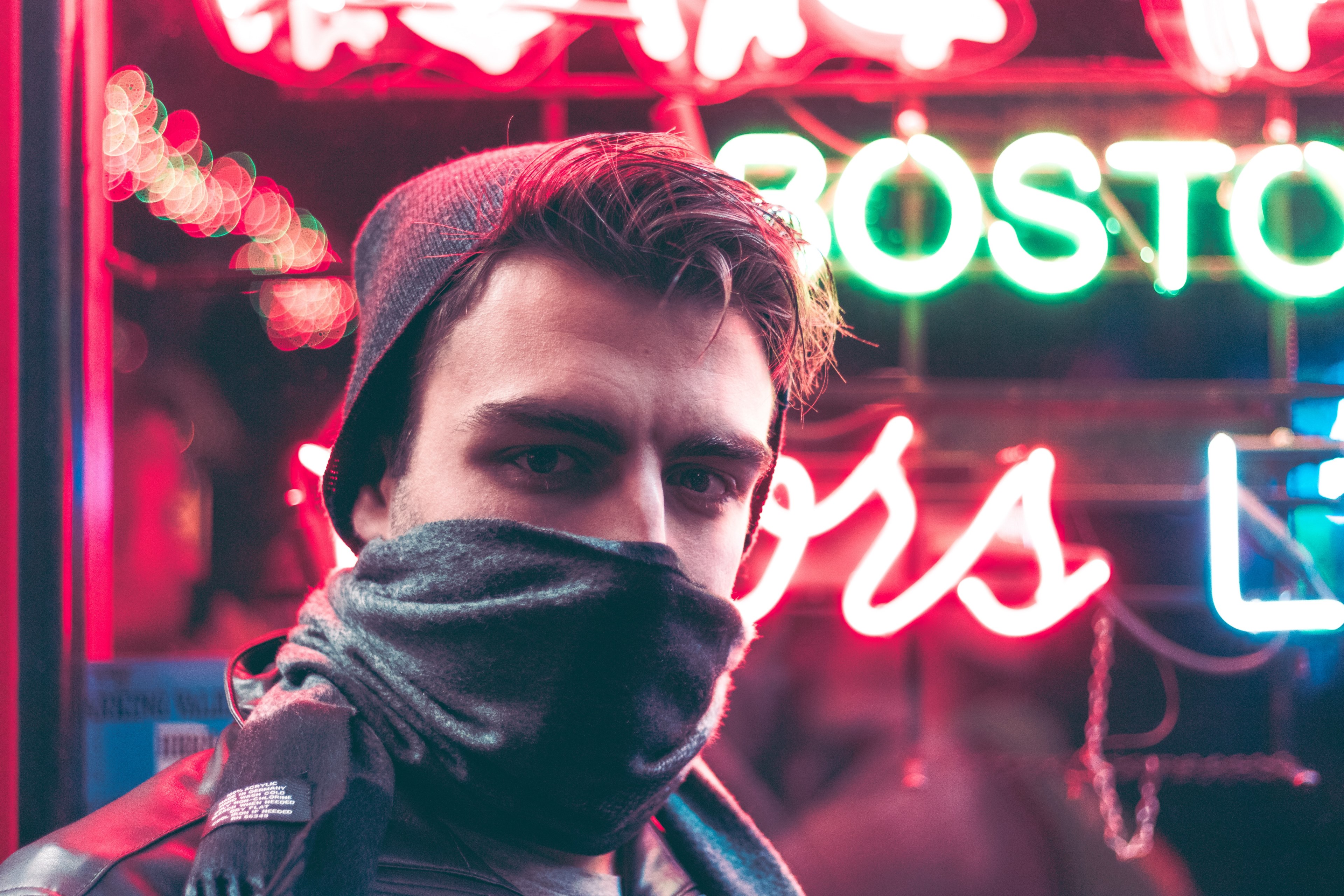 a man wearing a hat covering his face with a scarf and standing in front of a neon sign in boston, glass fractals 4k, HD Wallpaper