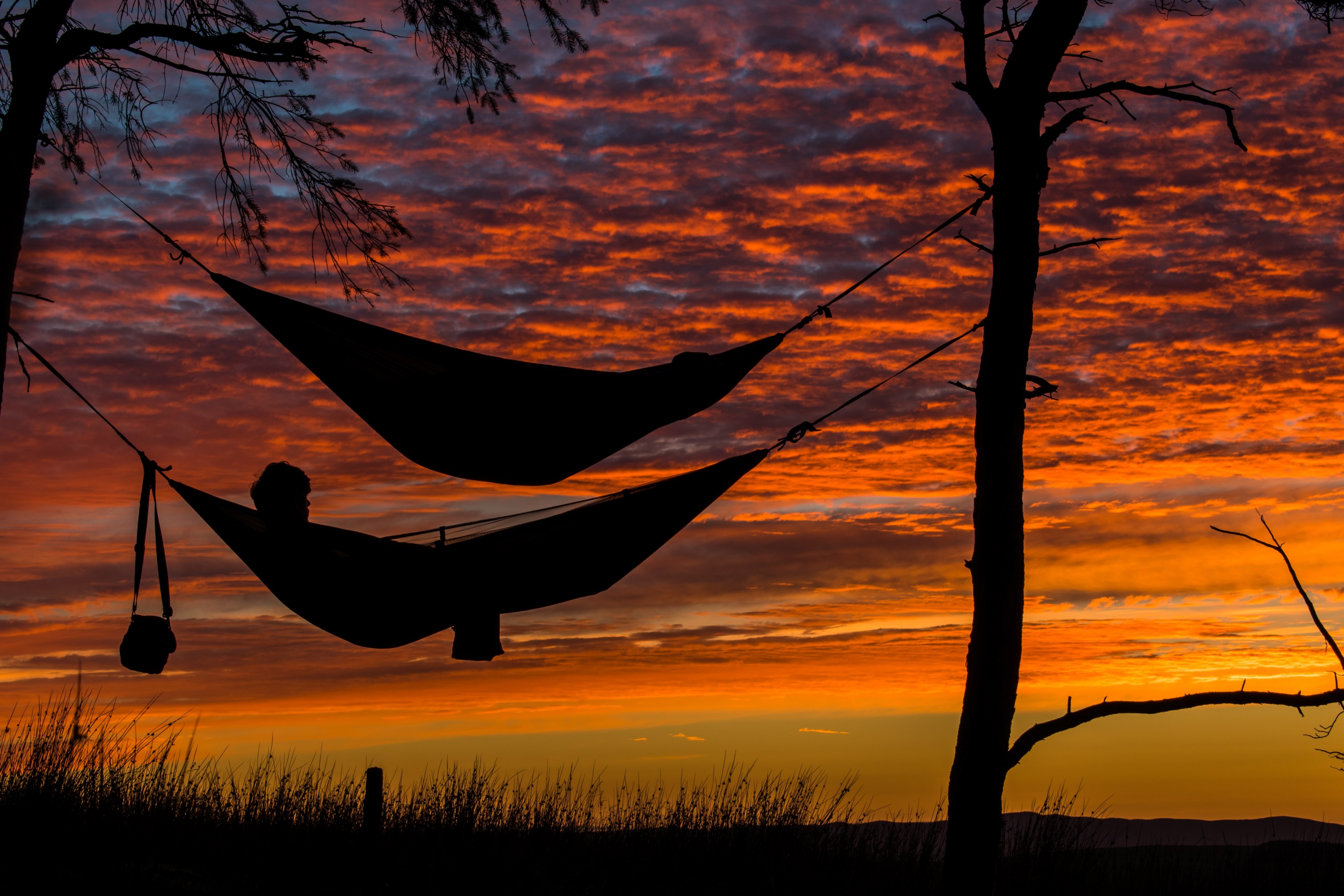the silhouettes of two people in hammocks against a deep red and orange sunset in neilston pad, neilston pad sunset 4k, HD Wallpaper
