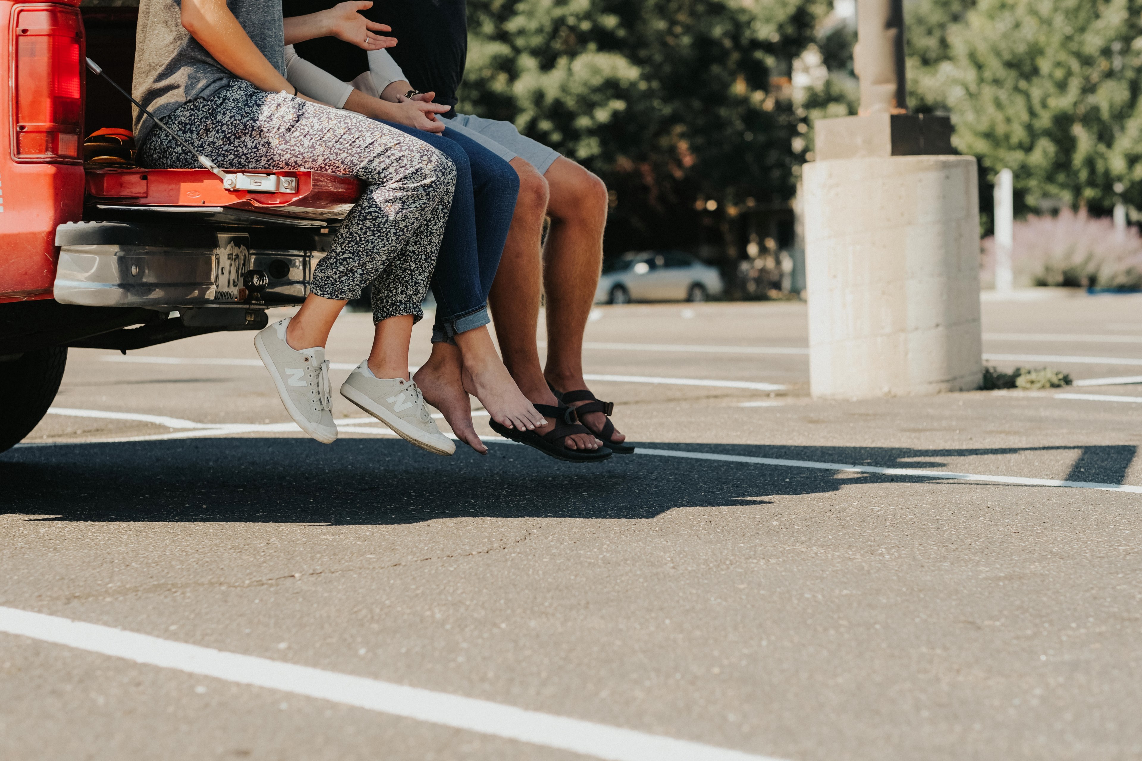 three people sitting on the tailgate of a red truck in a parking lot in fort collins, parking lot party 4k, HD Wallpaper