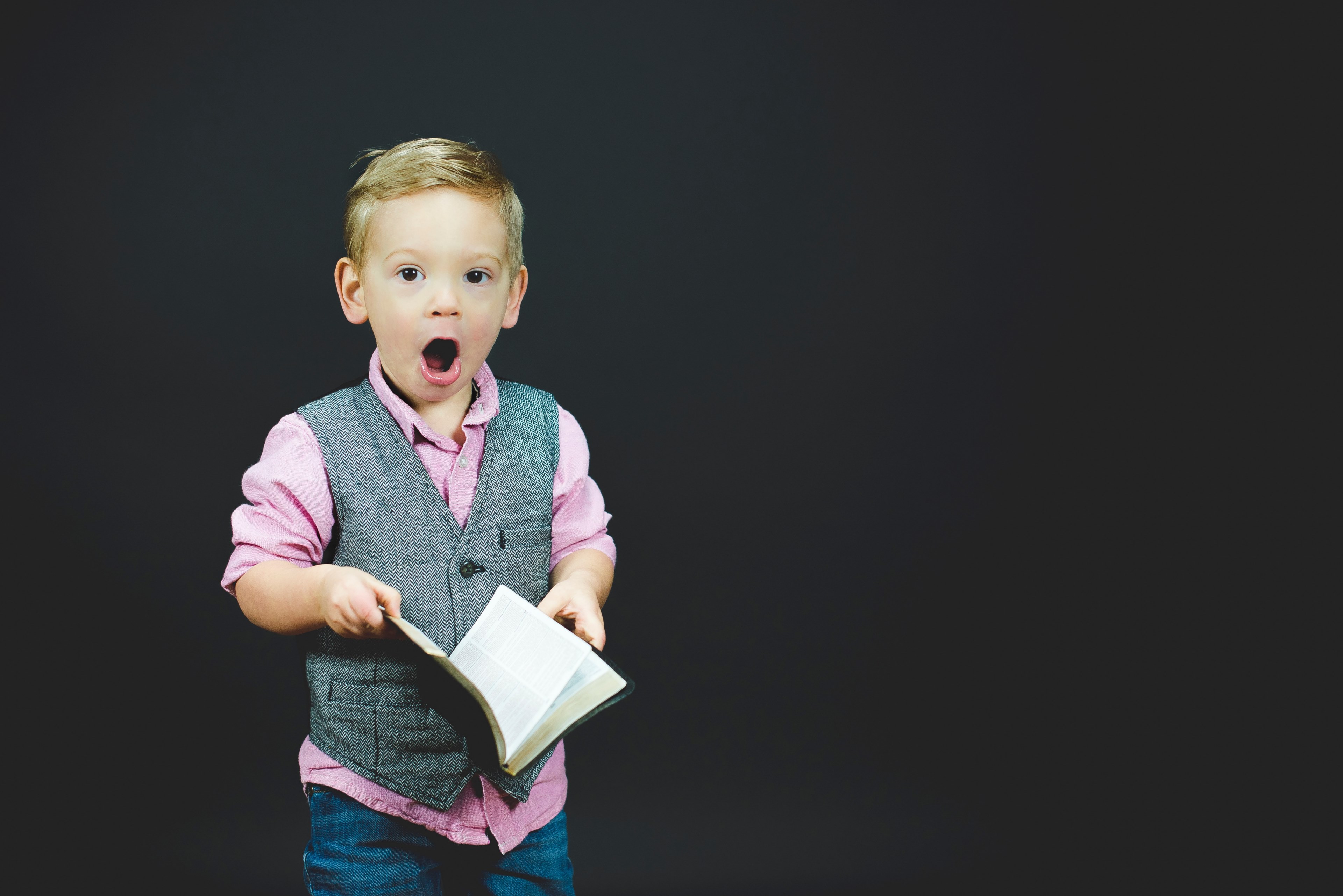 a little boy holding a book with a surprised expression on his face, the wonder of a book 4k, HD Wallpaper
