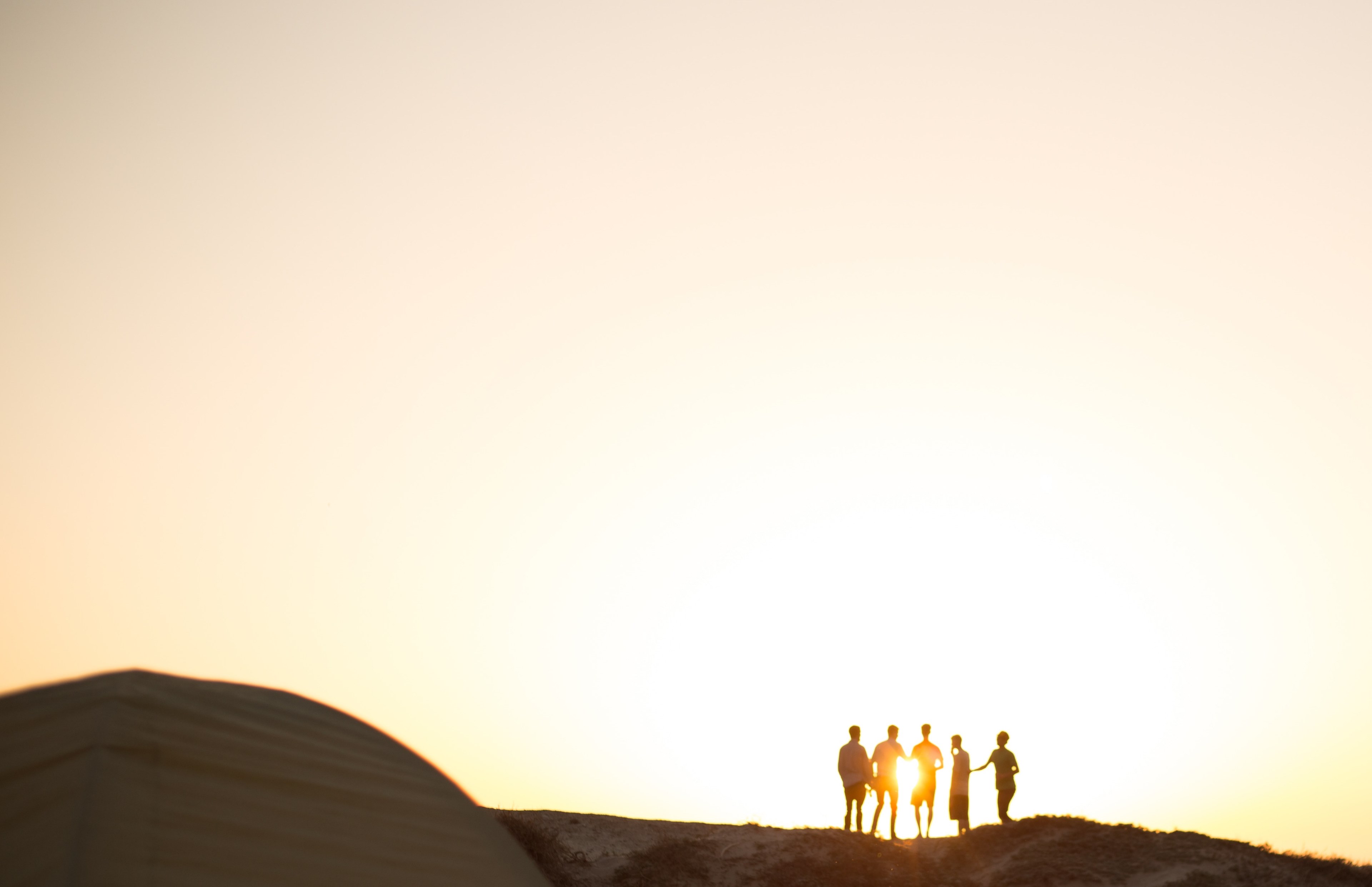 a silhouetted group of friends chatting on a hillside with the sun setting behind them at jalama beach county park, wasting the day away 4k, HD Wallpaper