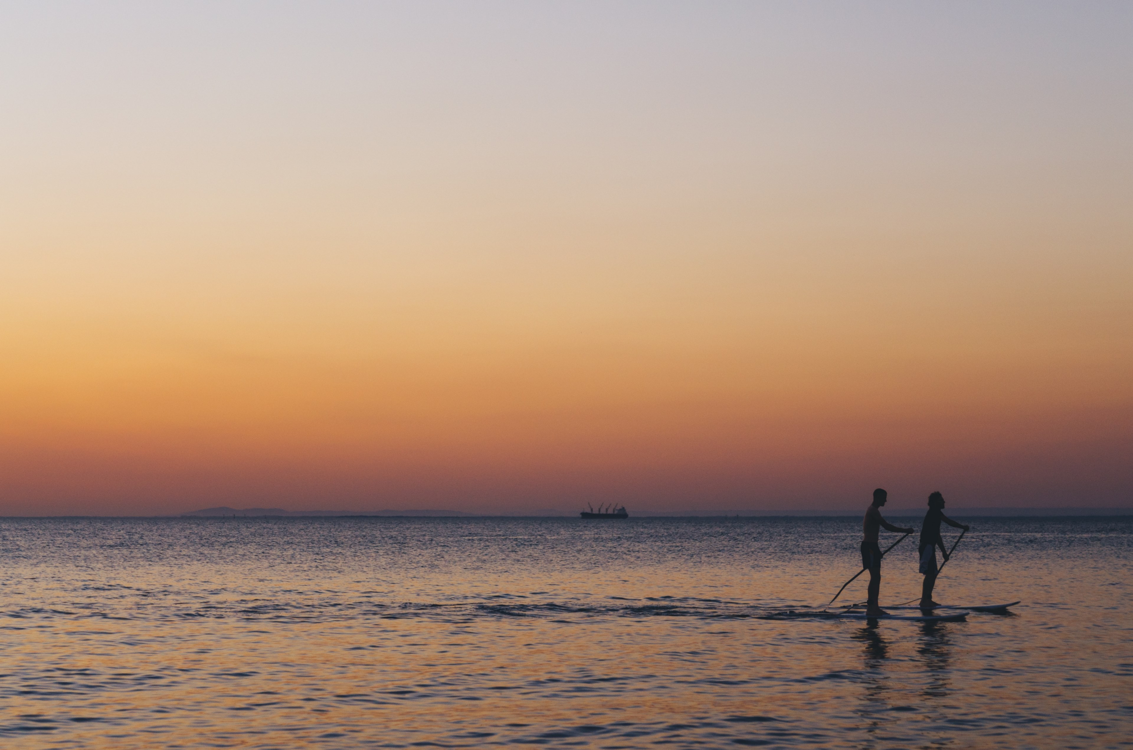two silhouettes paddleboarding through the calm ocean of brighton beach during a dull sunset, sunset paddleboarding in brighton 4k, HD Wallpaper