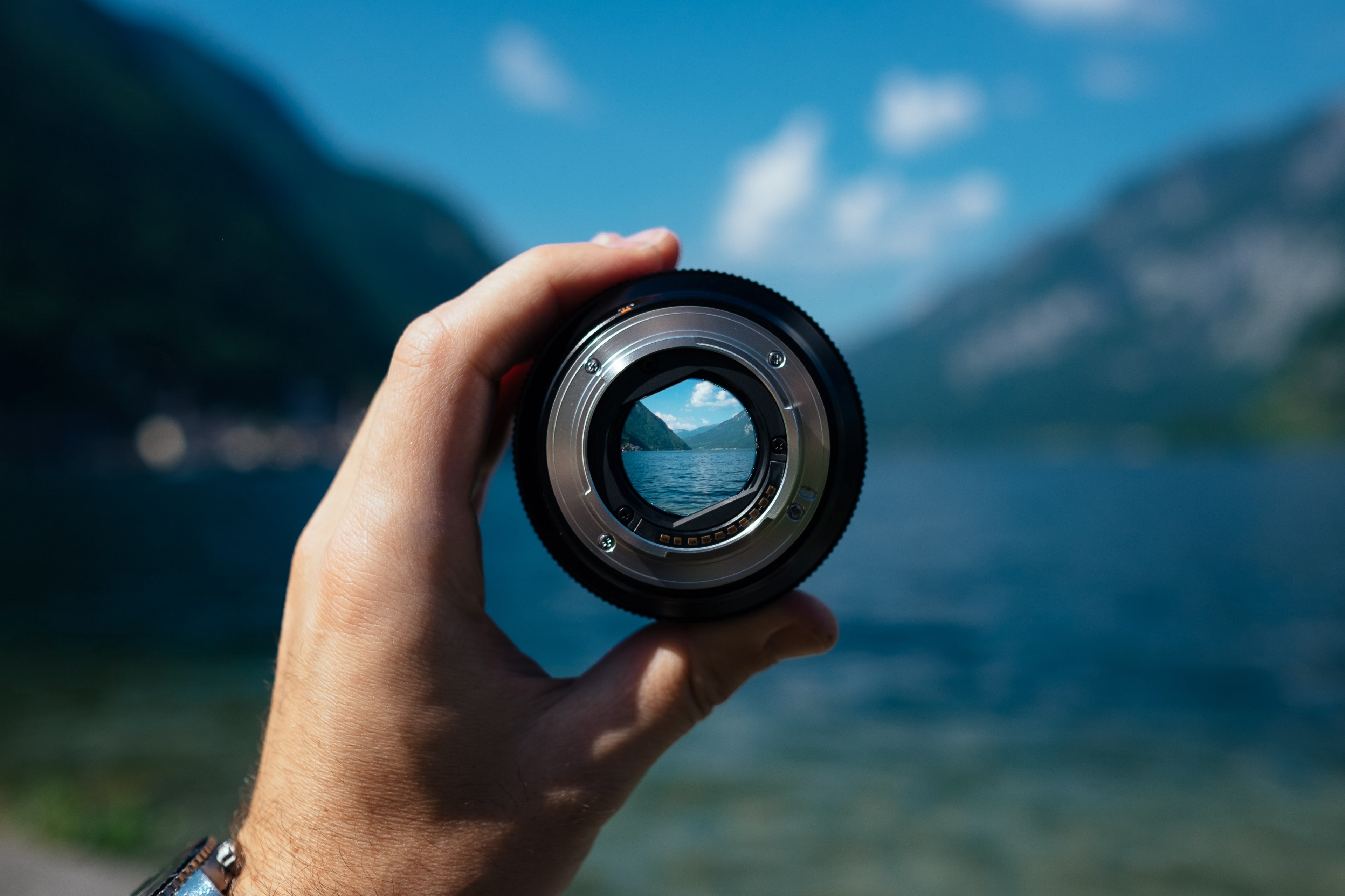 a persons hand holding a camera lens over a mountain lake, mountain lake in camera lens 4k, HD Wallpaper