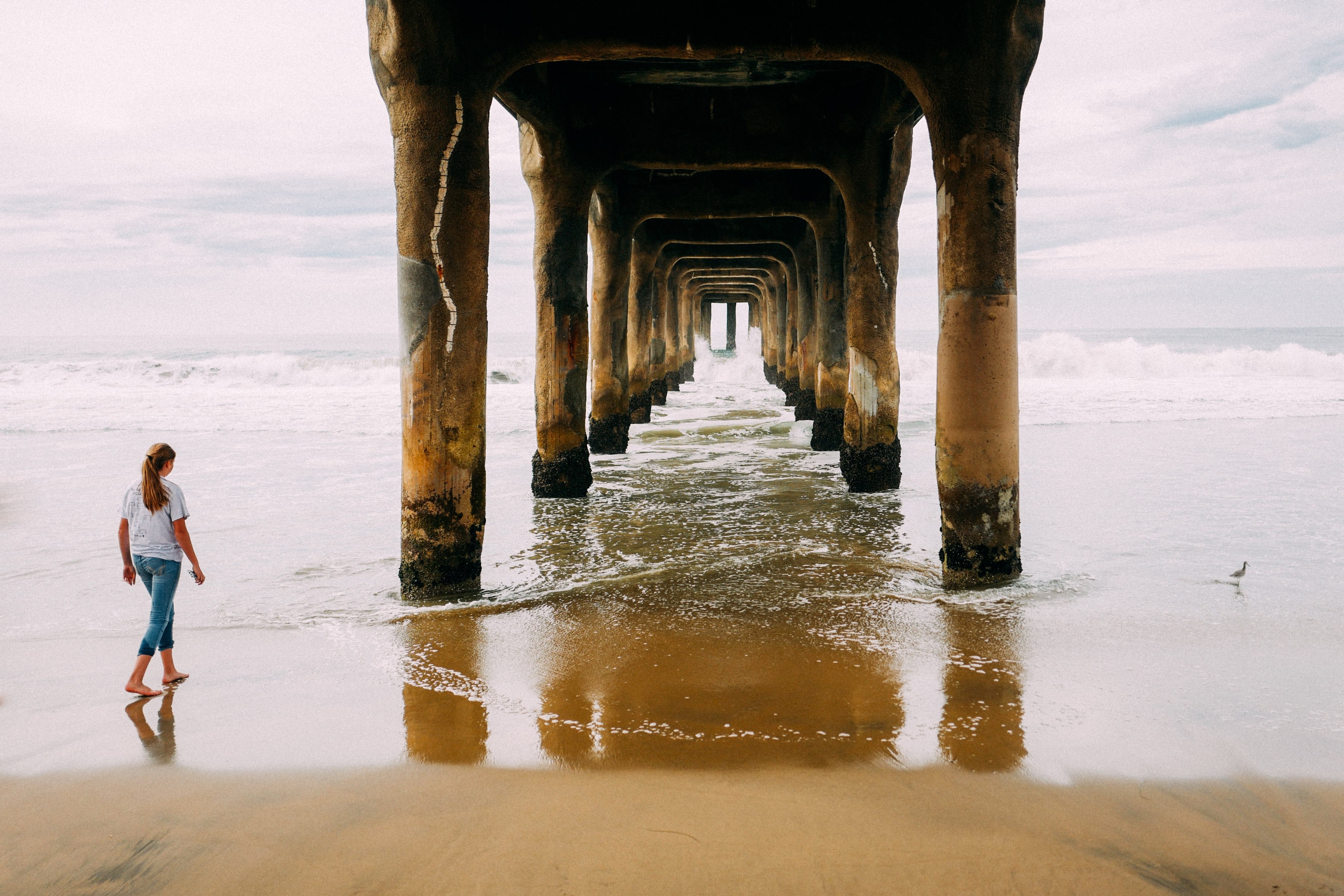 woman on the sand beach near wooden pillars of manhattan beach pier, girl underneath manhattan beach pier 4k, HD Wallpaper