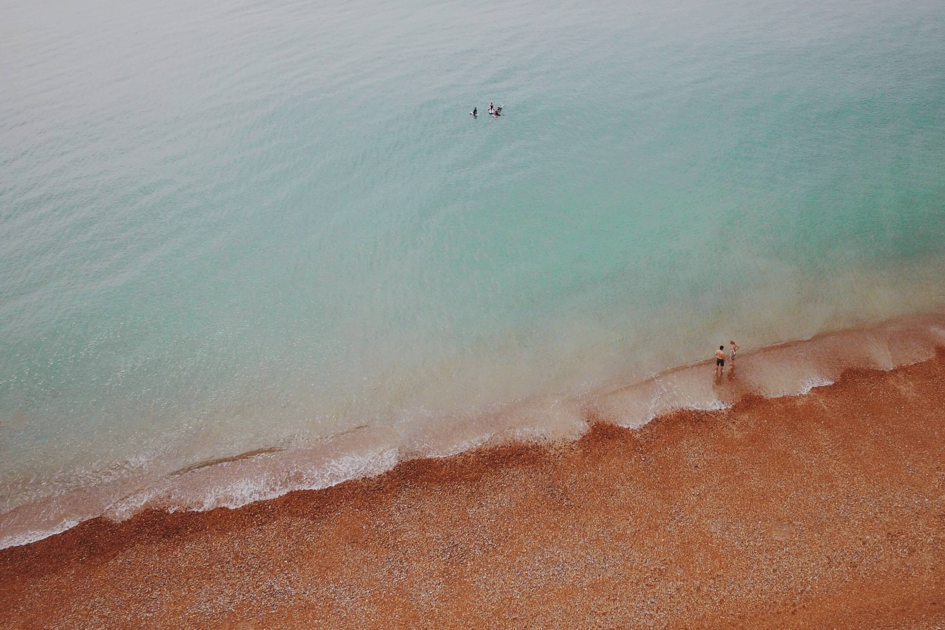 drone view of people swimming in clear ocean washing up on red sand beach in brighton, drone view of red sand beach 4k, HD Wallpaper