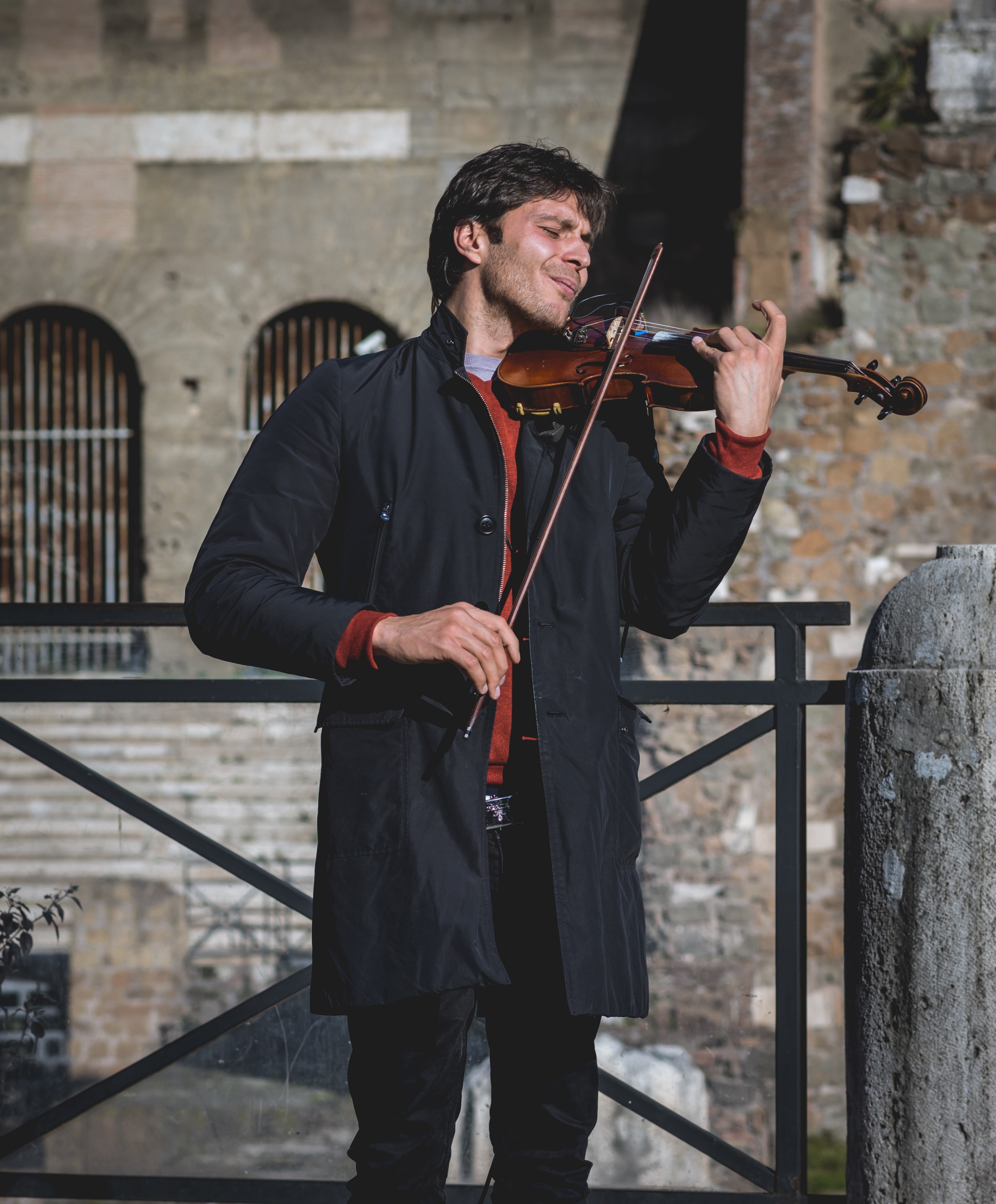 a man in a black coat playing the violet with his eyes closed in front of an old building, passionate violinist 4k, Phone HD Wallpaper