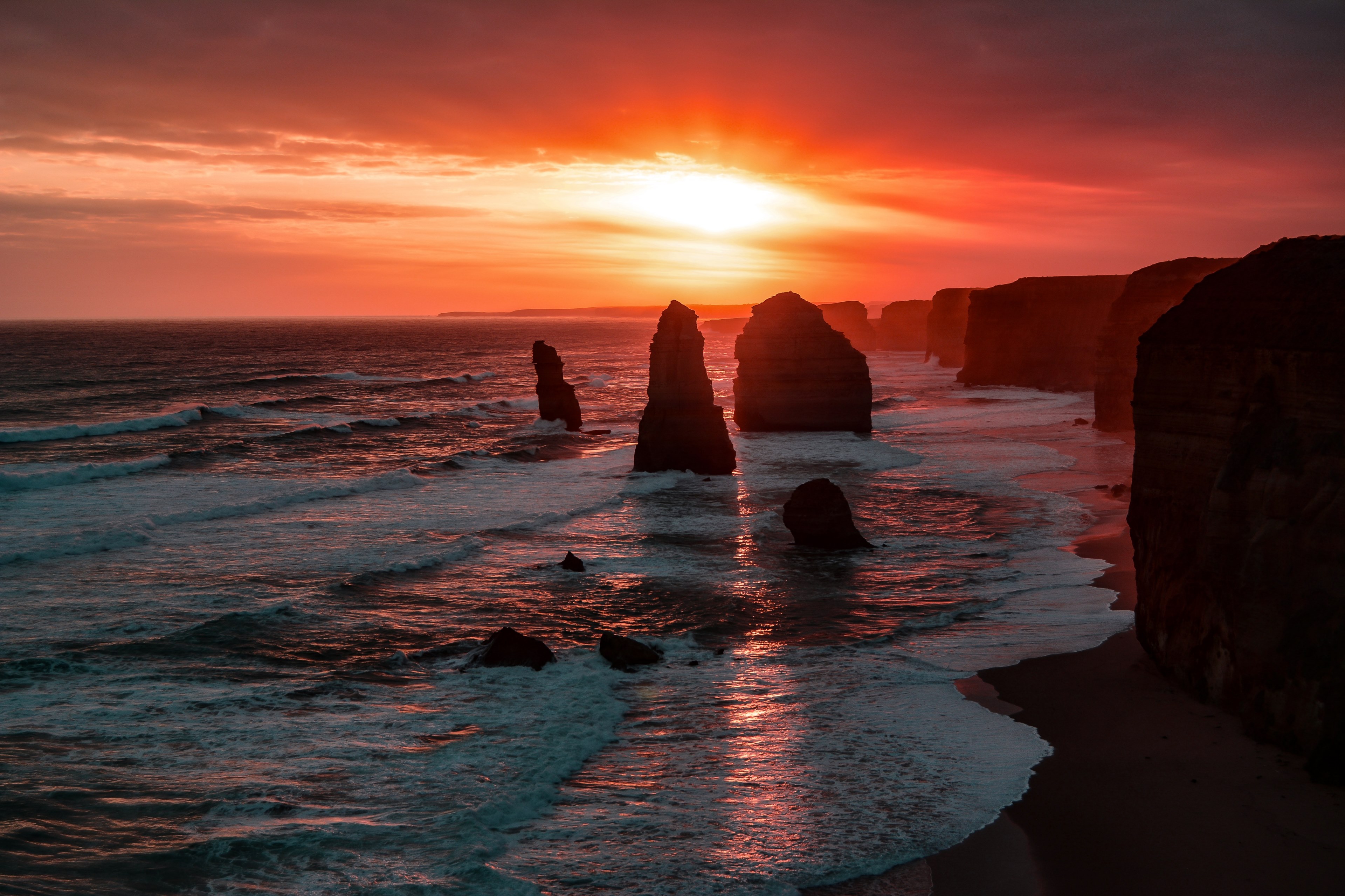 a blazing orange sun in a cloudy sky over australias twelve apostles coastal cliffs and waves, a world lost in time 4k, HD Wallpaper