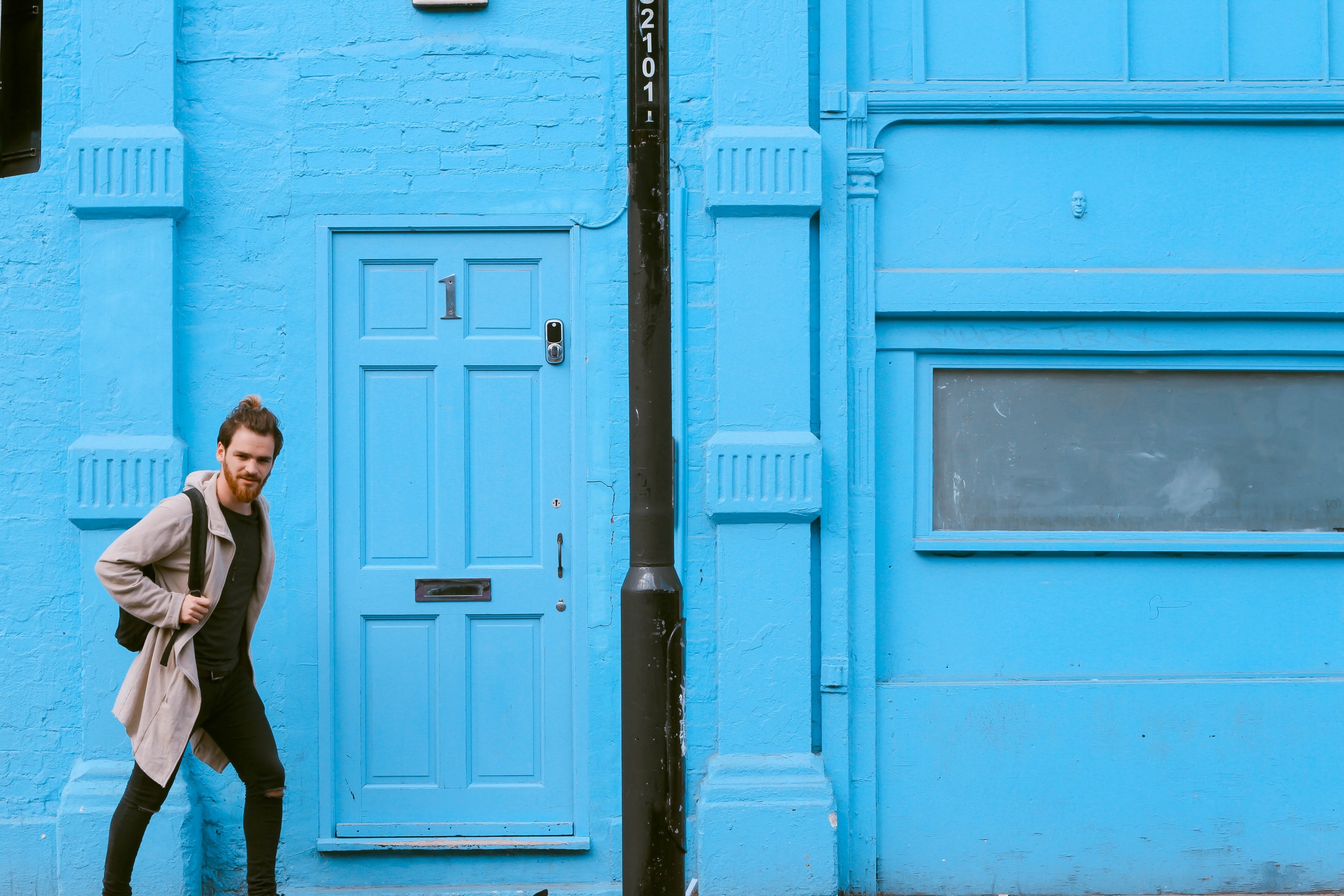 man with beard walks in front of a light blue building behind a lampost, streets of london 4k, HD Wallpaper