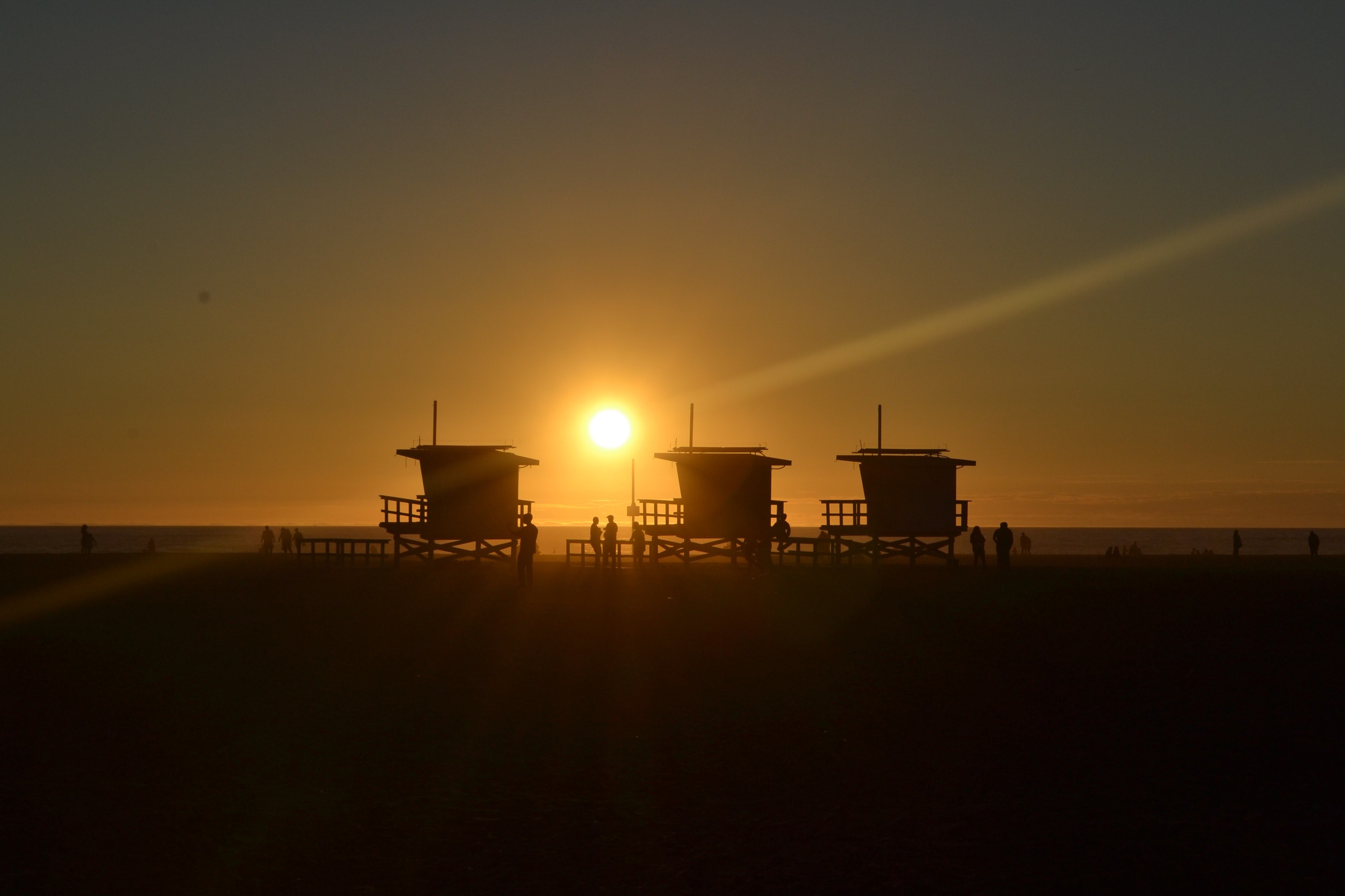 sun setting behind the silhouettes of three lifeguard stations at venice beach, lifeguard stations at sunset 4k, HD Wallpaper