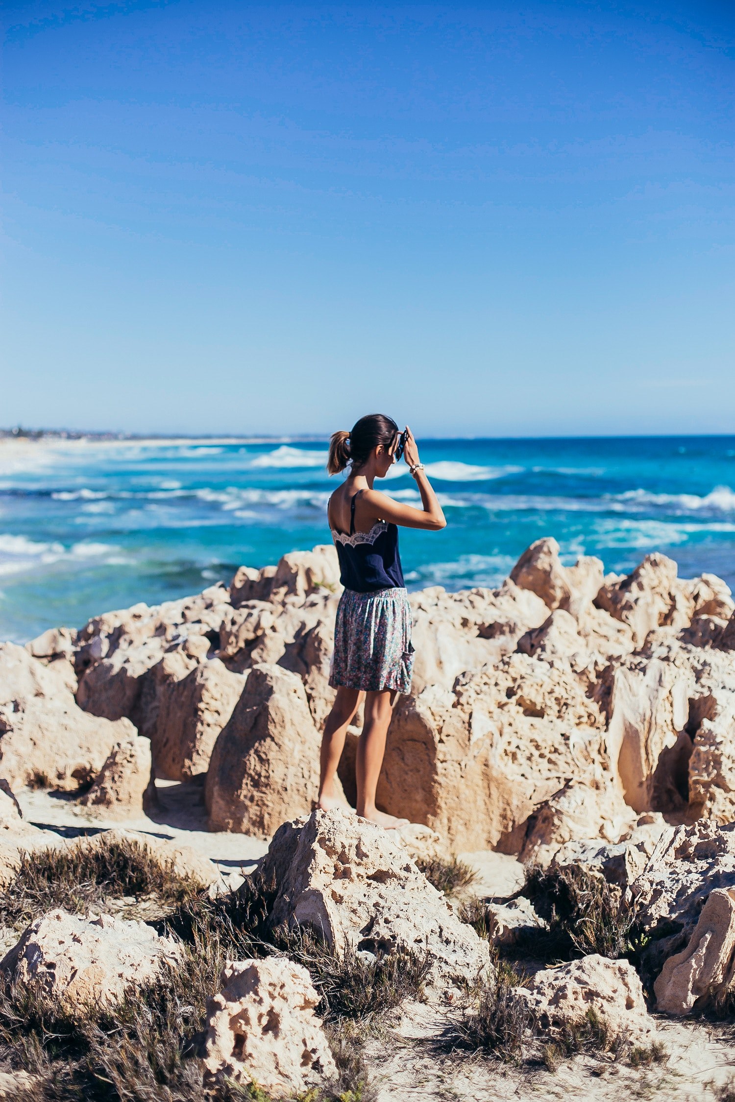 woman in a skirt standing on the rocks at the trigg beach coastline, woman standing on the rocks 4k, Phone HD Wallpaper