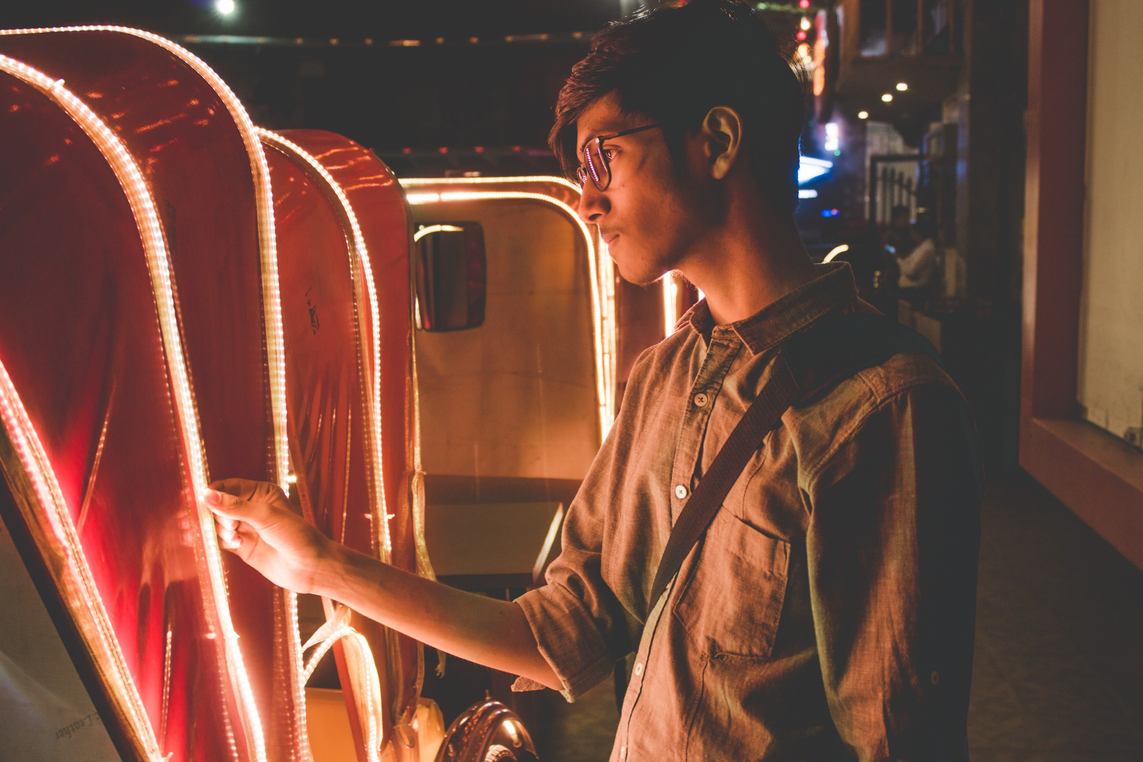 young hipster man looks at the lights lining a carriage on a dark city street, observing the lights 4k, HD Wallpaper