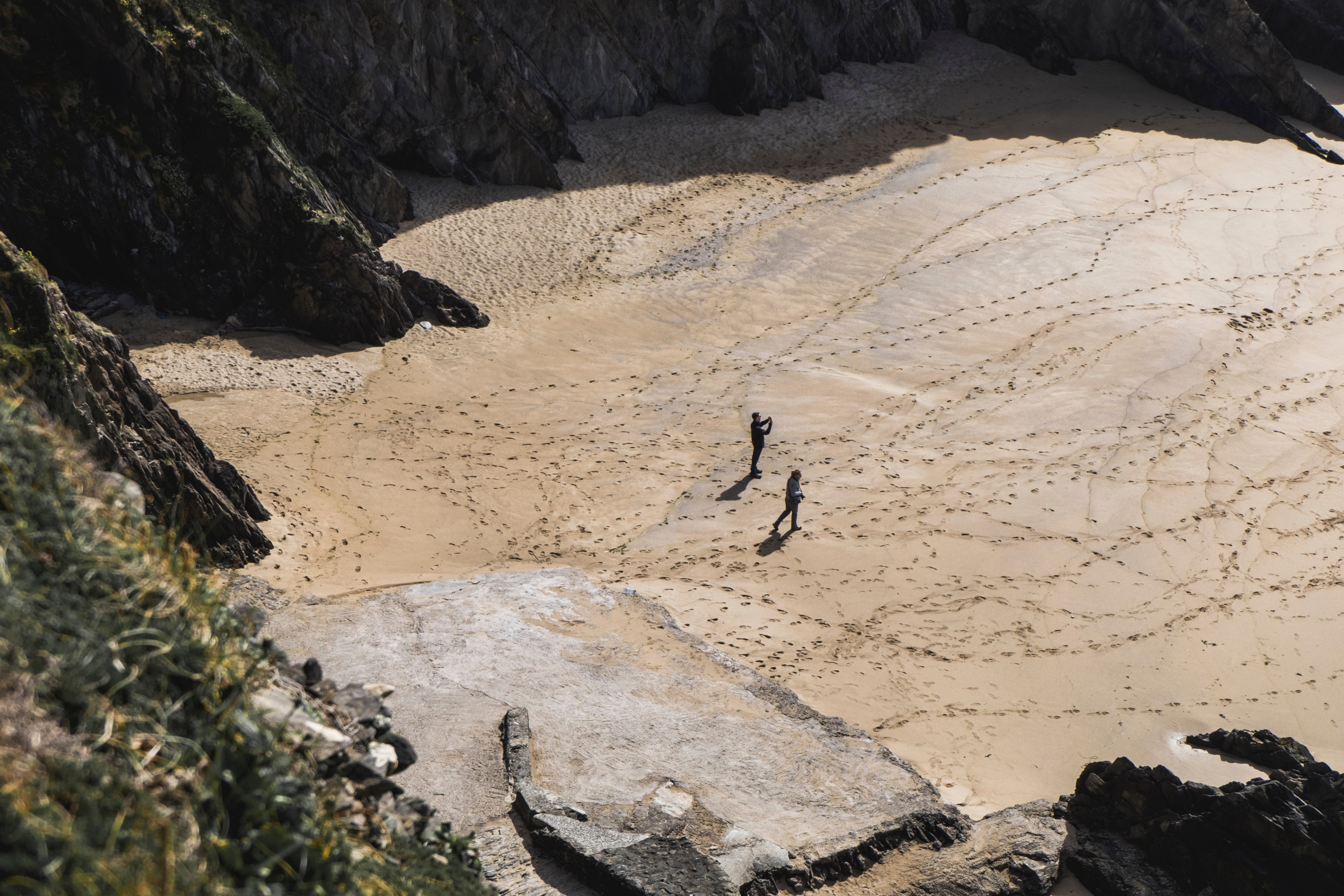 two people on a sand beach full of footprints between rock cliffs, two people on the sand beach 4k, HD Wallpaper