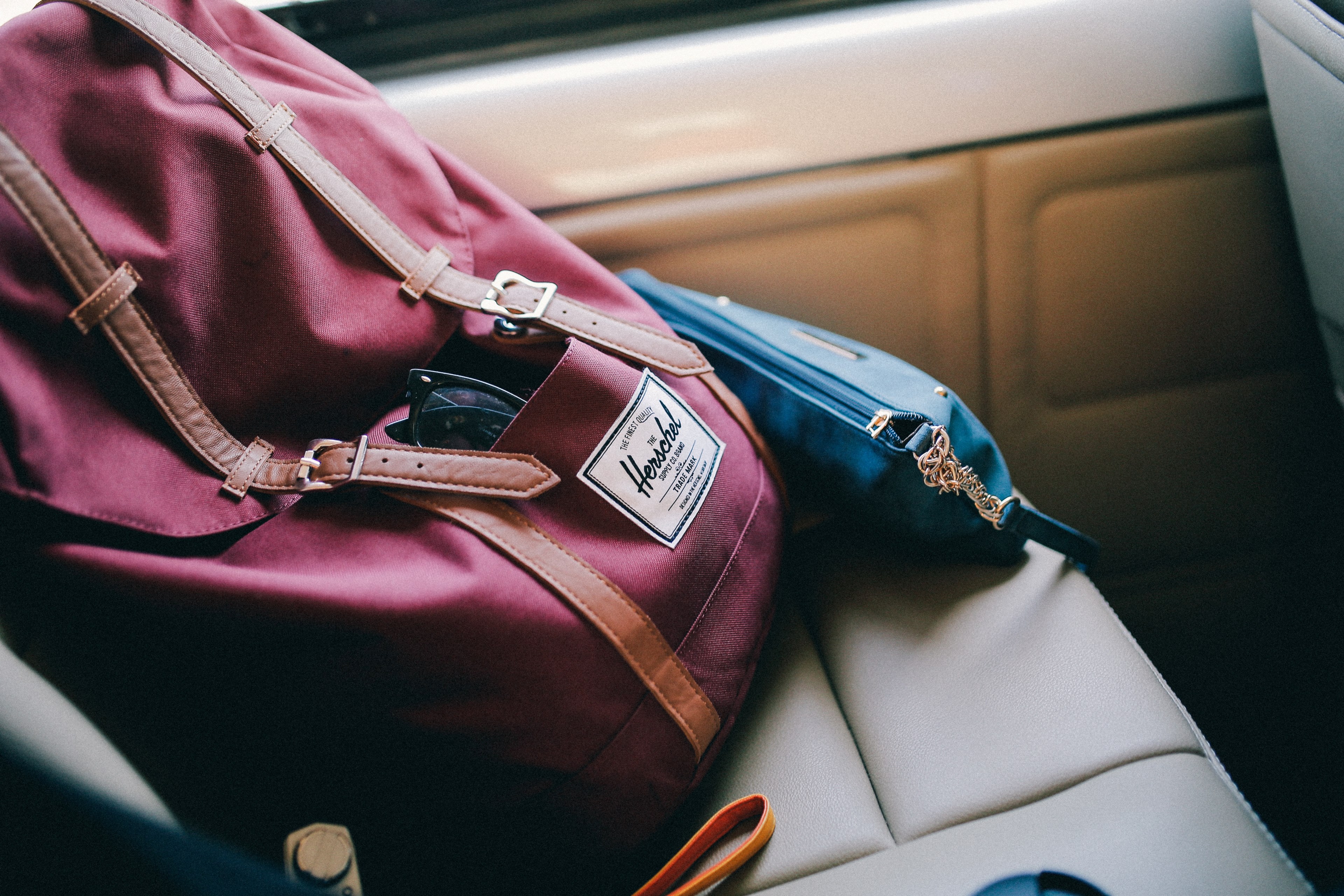 red herschel backpack with leather straps and a blue purse on the leather seat, backpack purse on seat 4k, HD Wallpaper